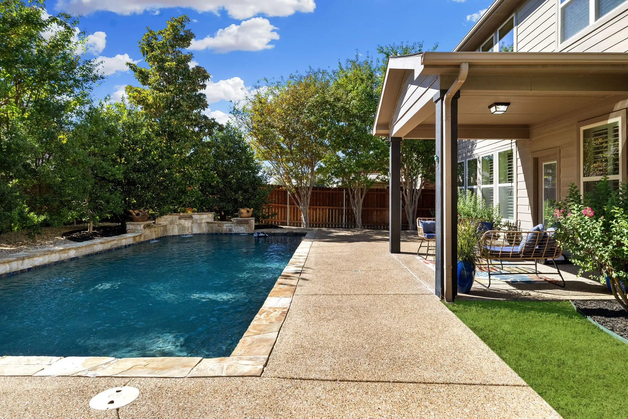In-ground swimming pool with stone coping and water feature