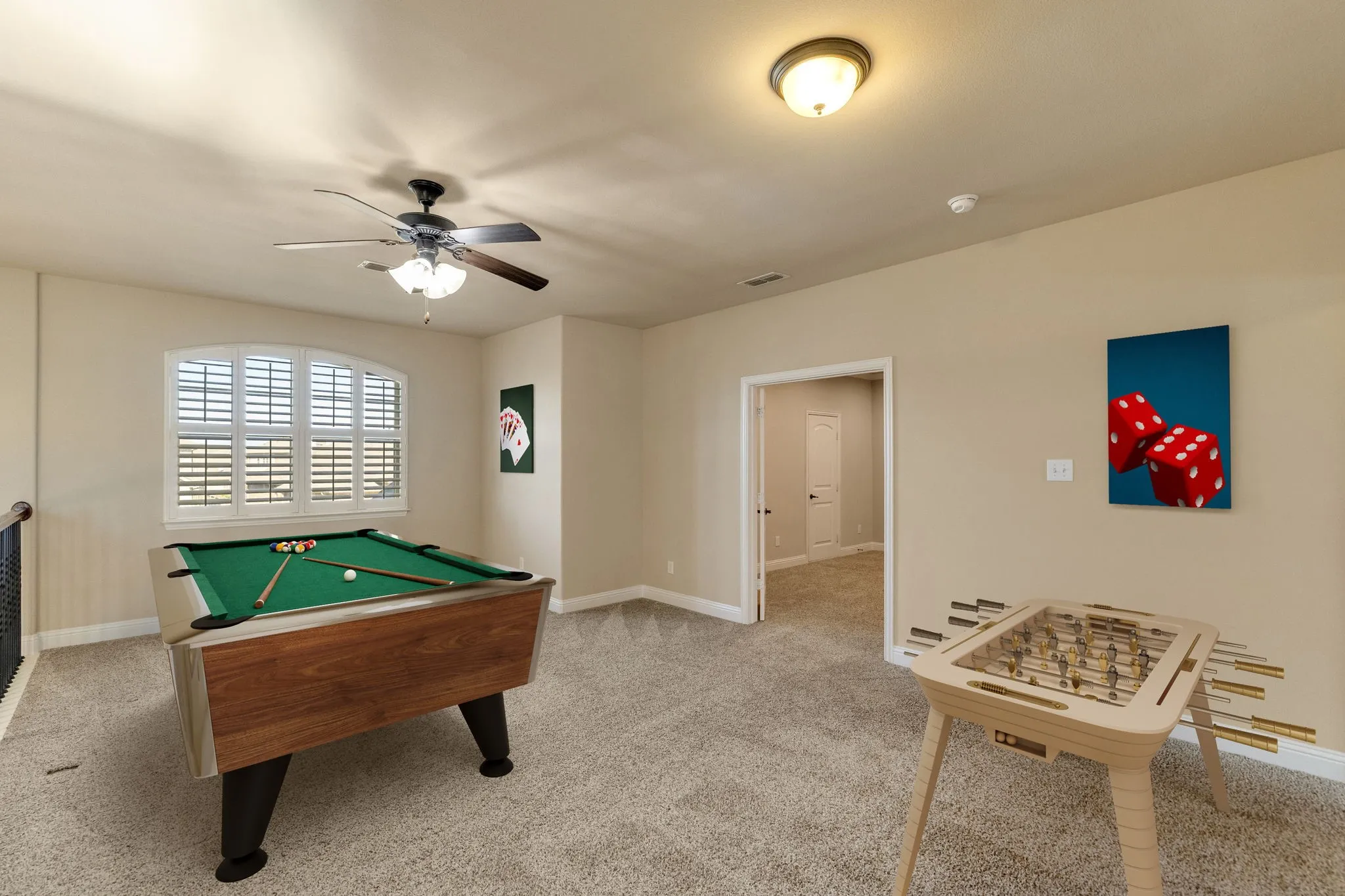 Spacious bonus room featuring carpet flooring, an arched window with plantation shutters, a ceiling fan with integrated lighting, and neutral wall tones