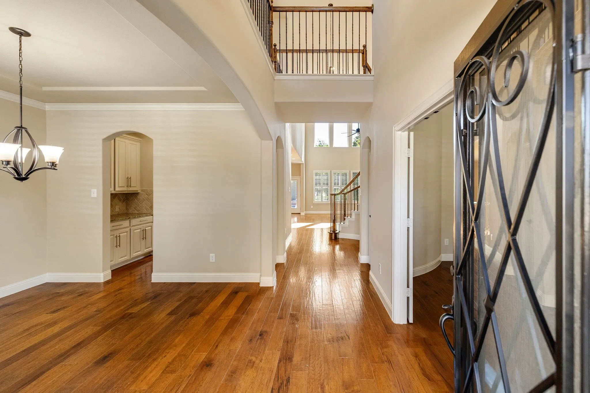 Hardwood flooring throughout, a two-story foyer, iron-spindled balustrade, and an arched entryway to butlers pantry Off of Formal Dining area.