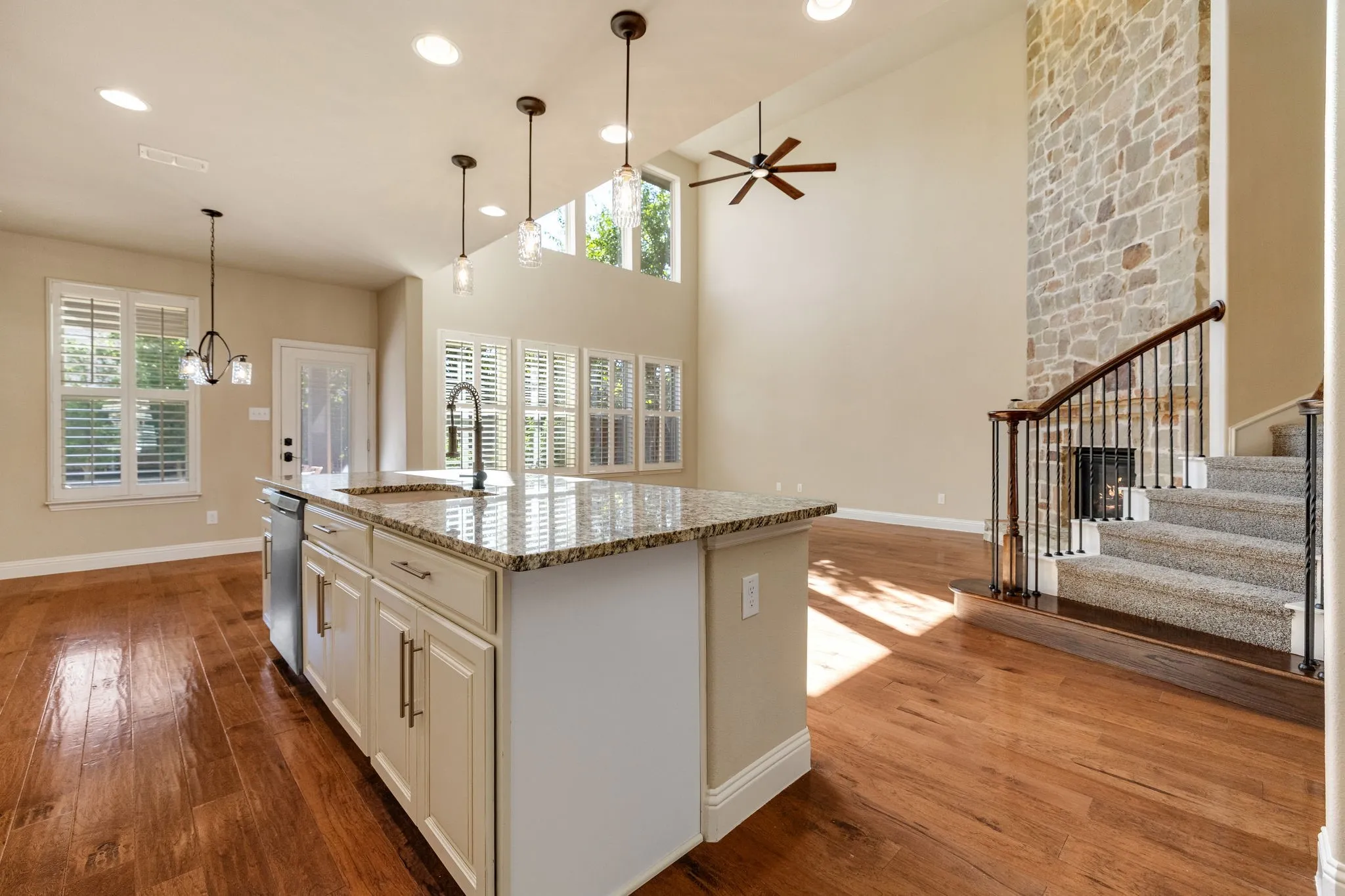Kitchen island with a granite countertop, undermount sink, and pendant lighting