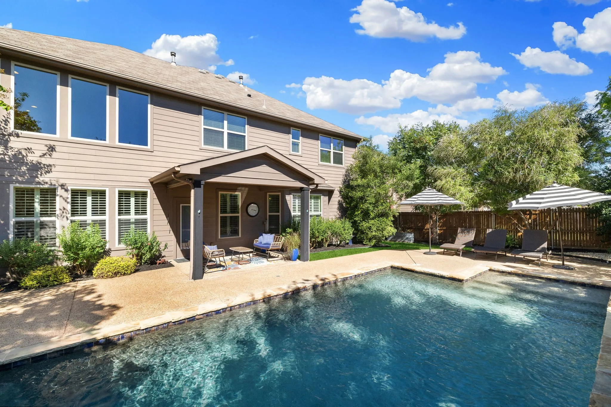 Expansive inground swimming pool with integrated steps, surrounded by a concrete patio