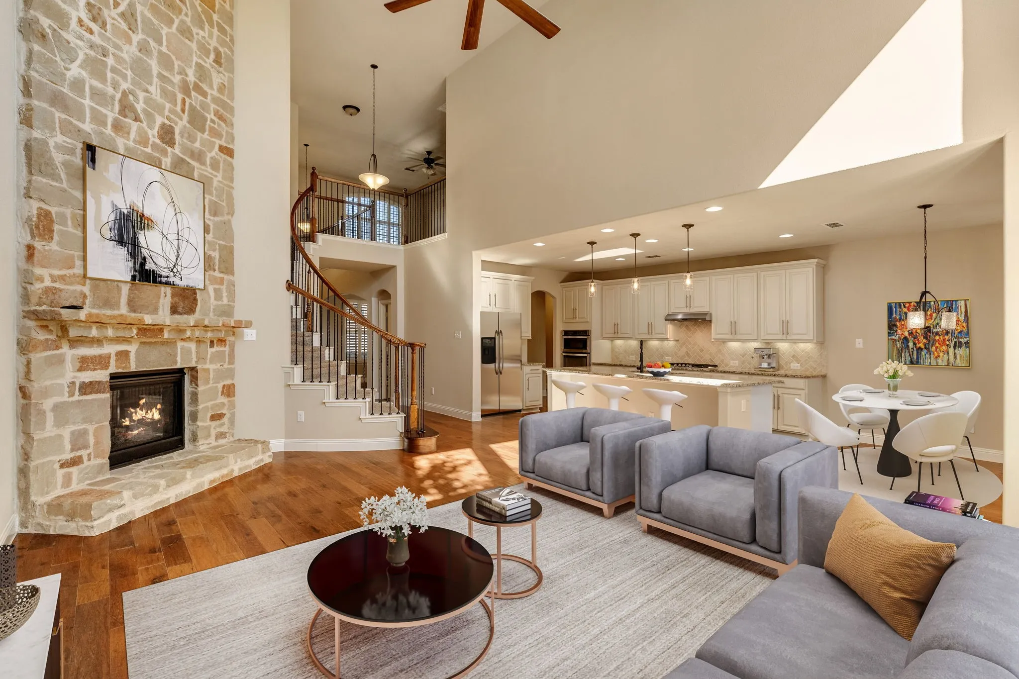 Two-story living area featuring a stone-clad fireplace and wood-finish flooring