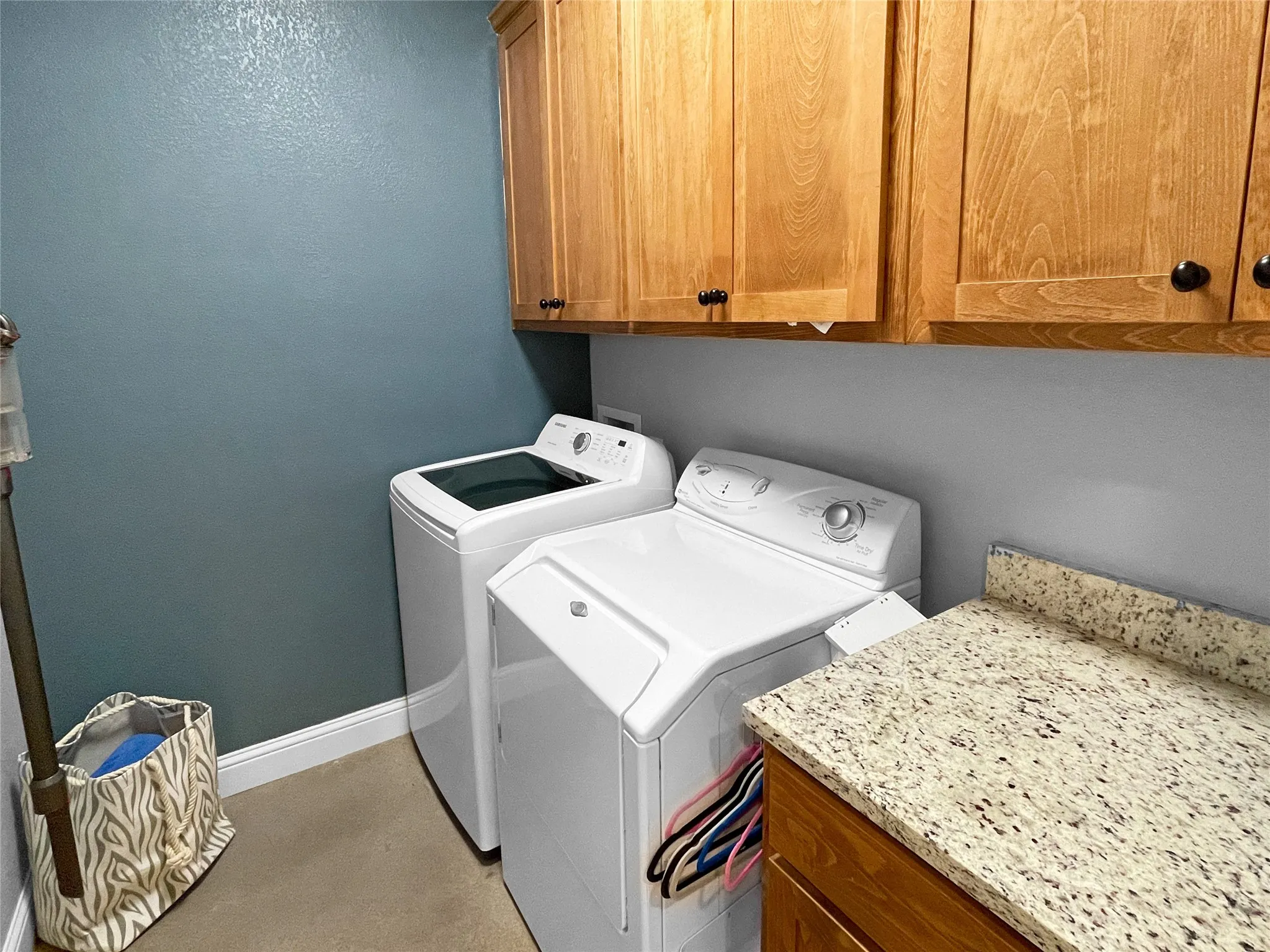 Laundry area featuring upper wood-finish cabinetry, a light-colored countertop, and a built-in lower cabinet