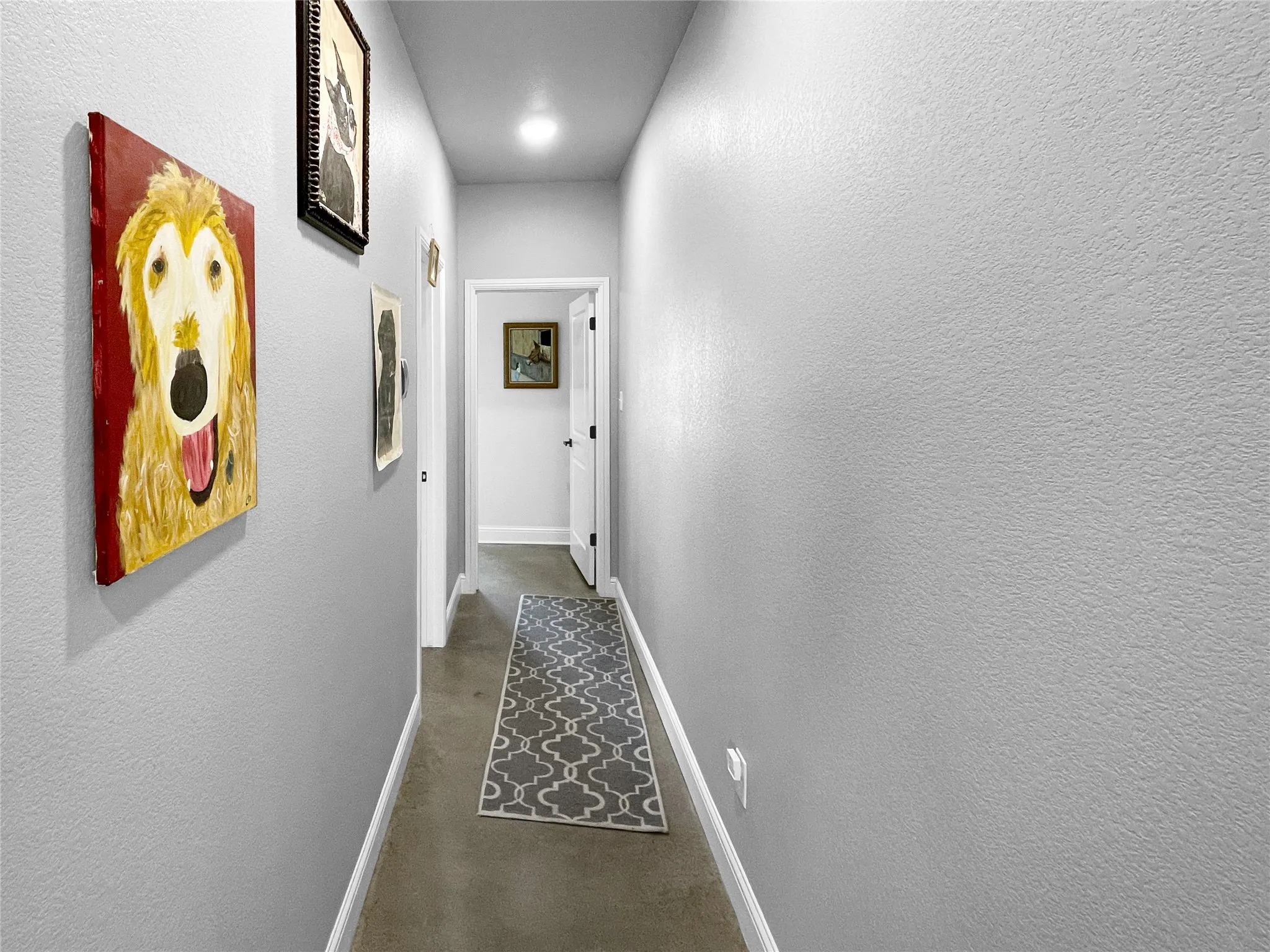 Recessed lighting illuminates a hallway with light gray walls and white trim, featuring a dark brown flooring