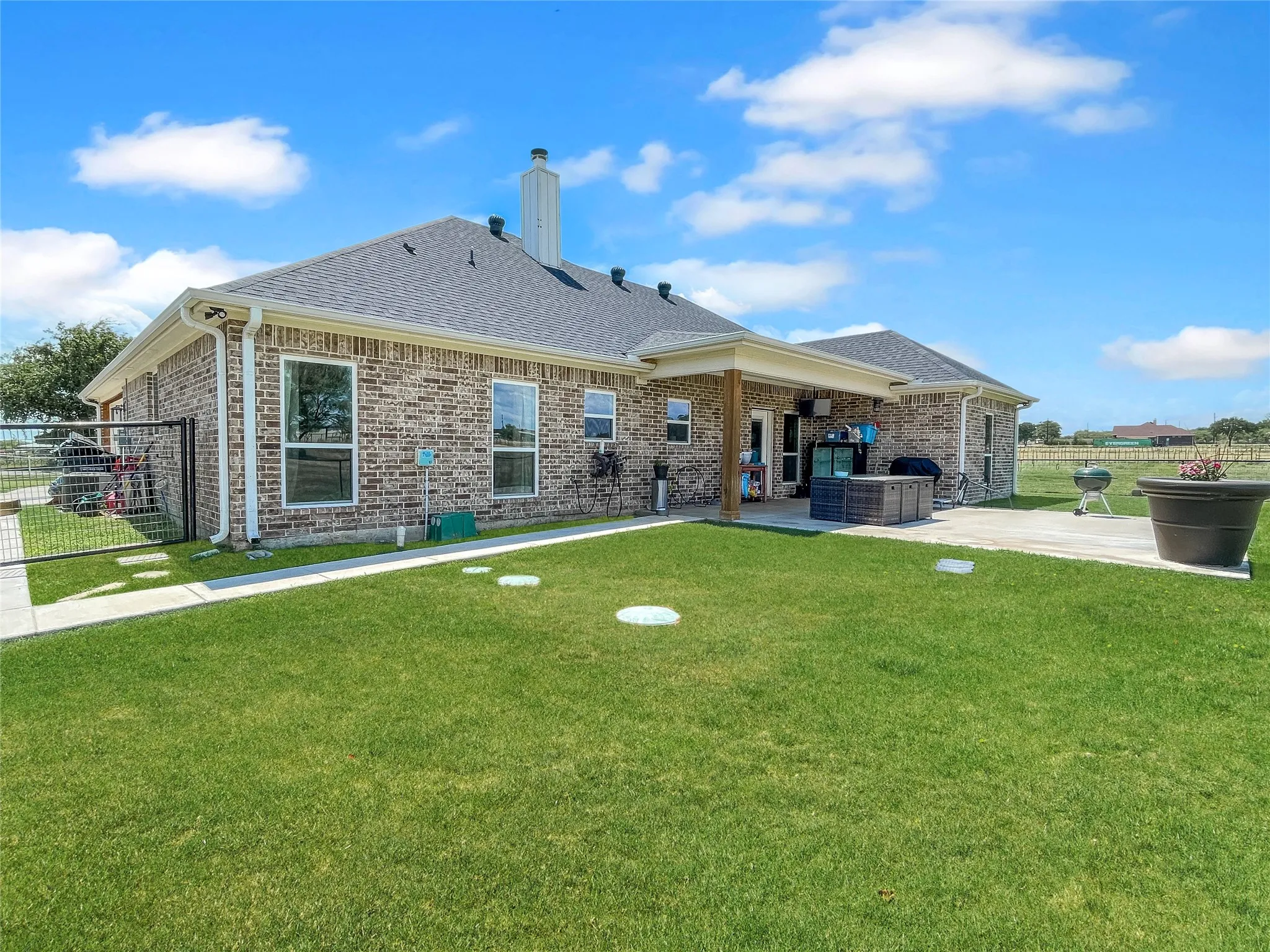 Brick exterior with white trim, dark shingle roof, and an expansive lawn
