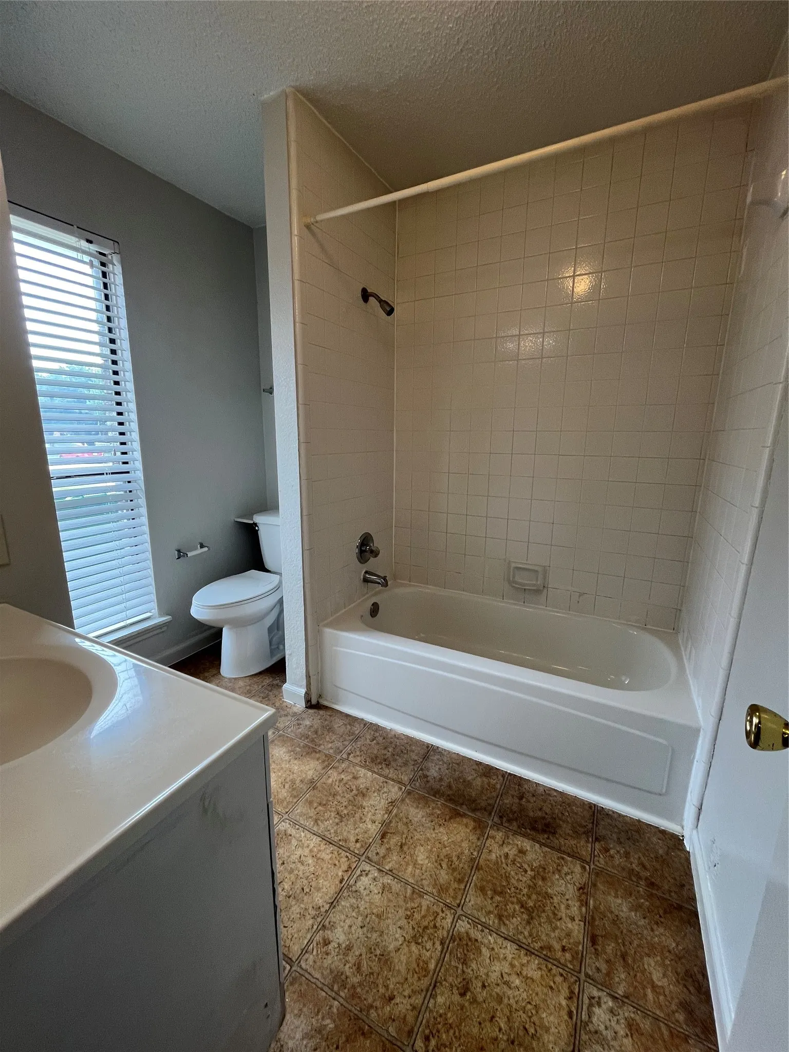 Full bathroom featuring vanity, tiled shower / bath, toilet, a textured ceiling, and tile patterned flooring