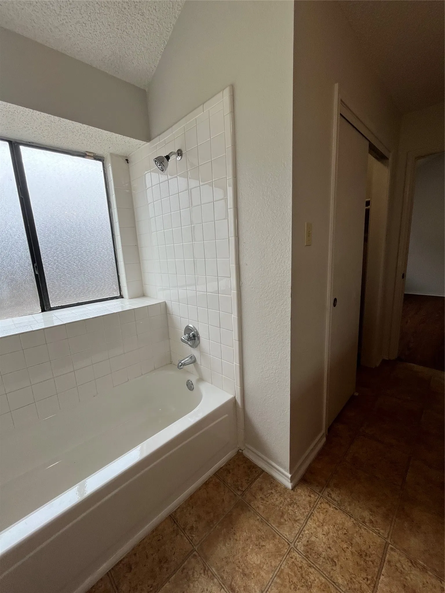 Bathroom with tile patterned floors, tiled shower / bath combo, and a textured ceiling