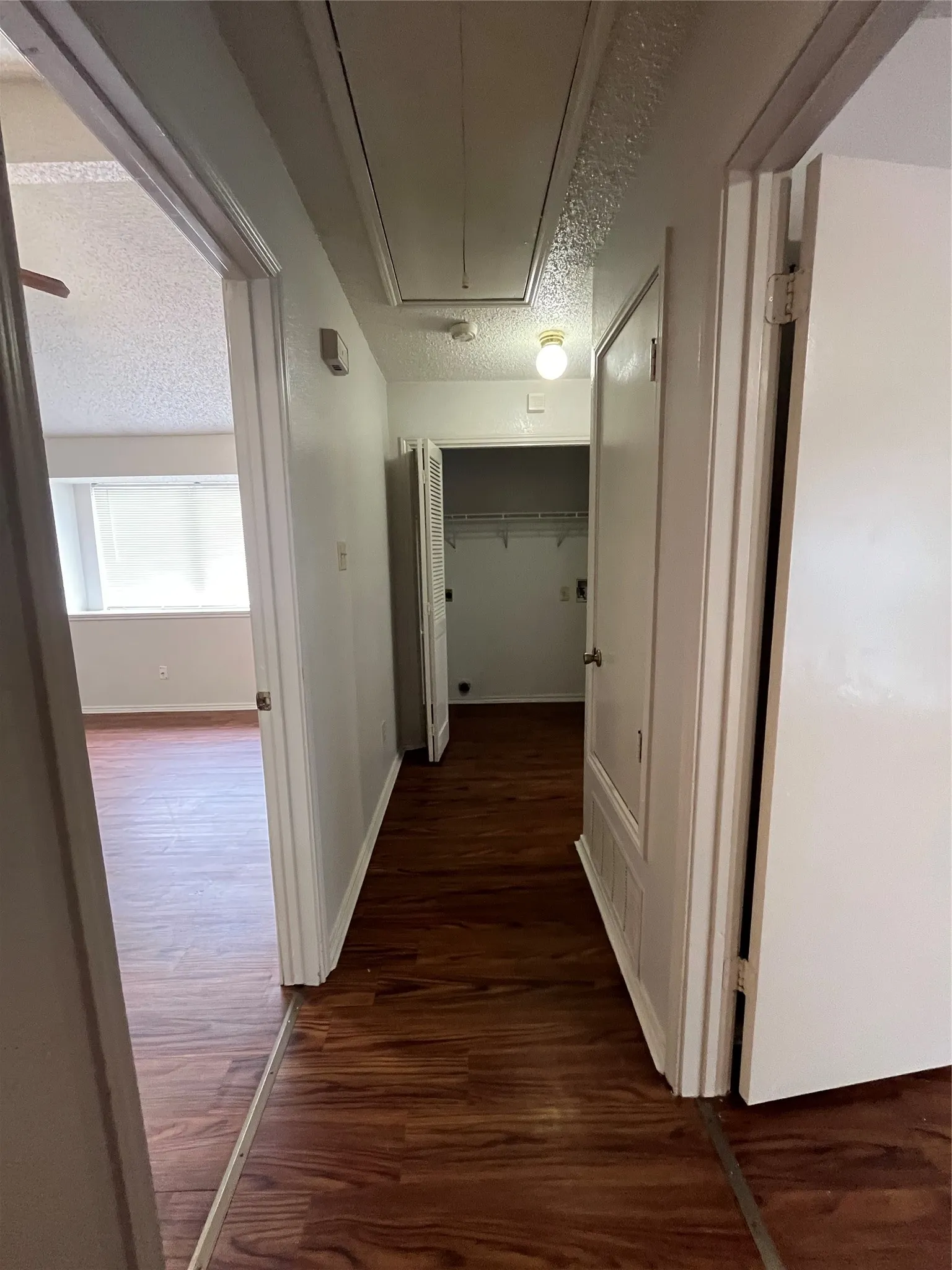 Hallway with dark hardwood / wood-style floors and a textured ceiling
