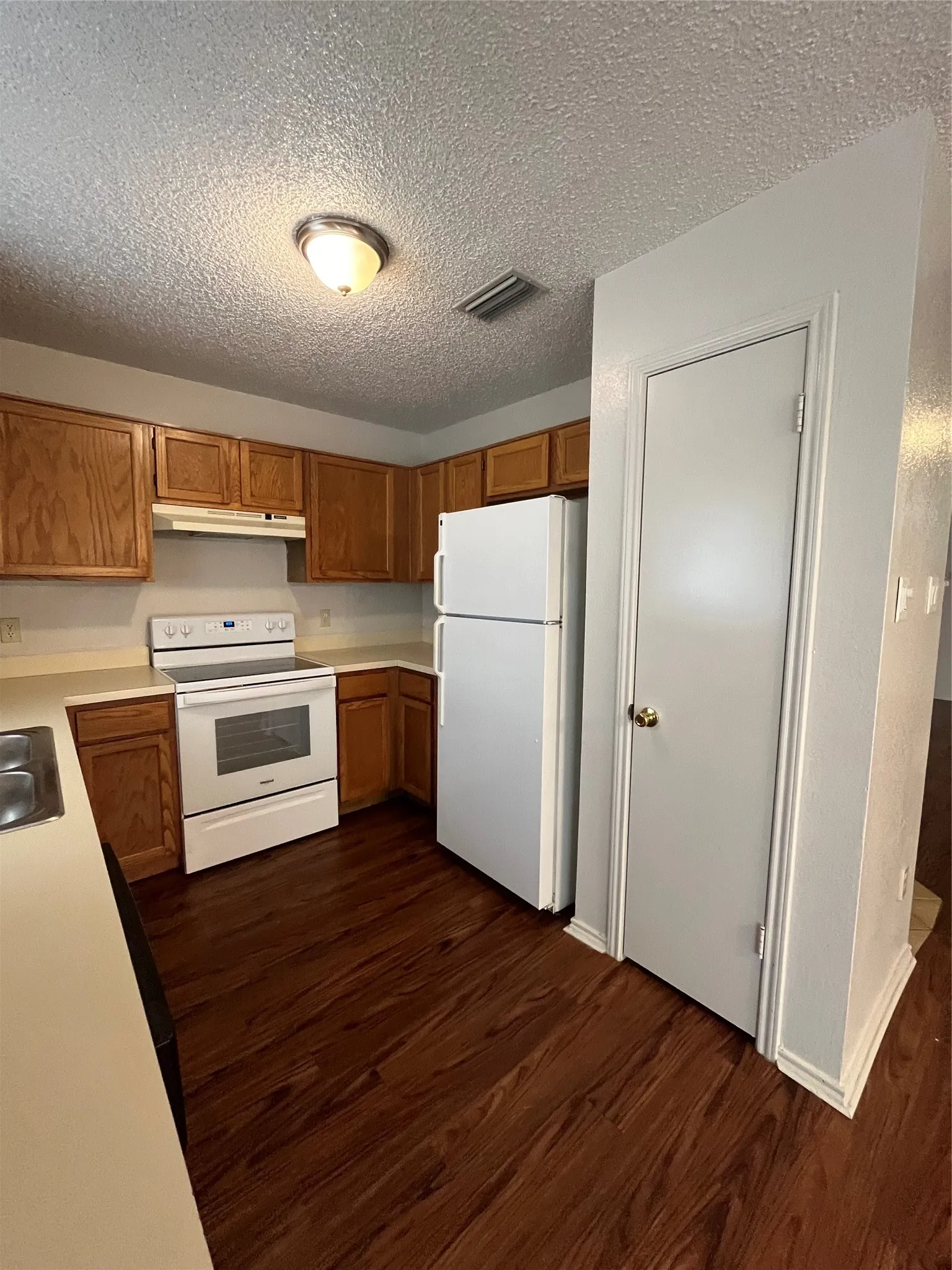 Kitchen featuring extractor fan, dark hardwood / wood-style flooring, white refrigerator, and stove