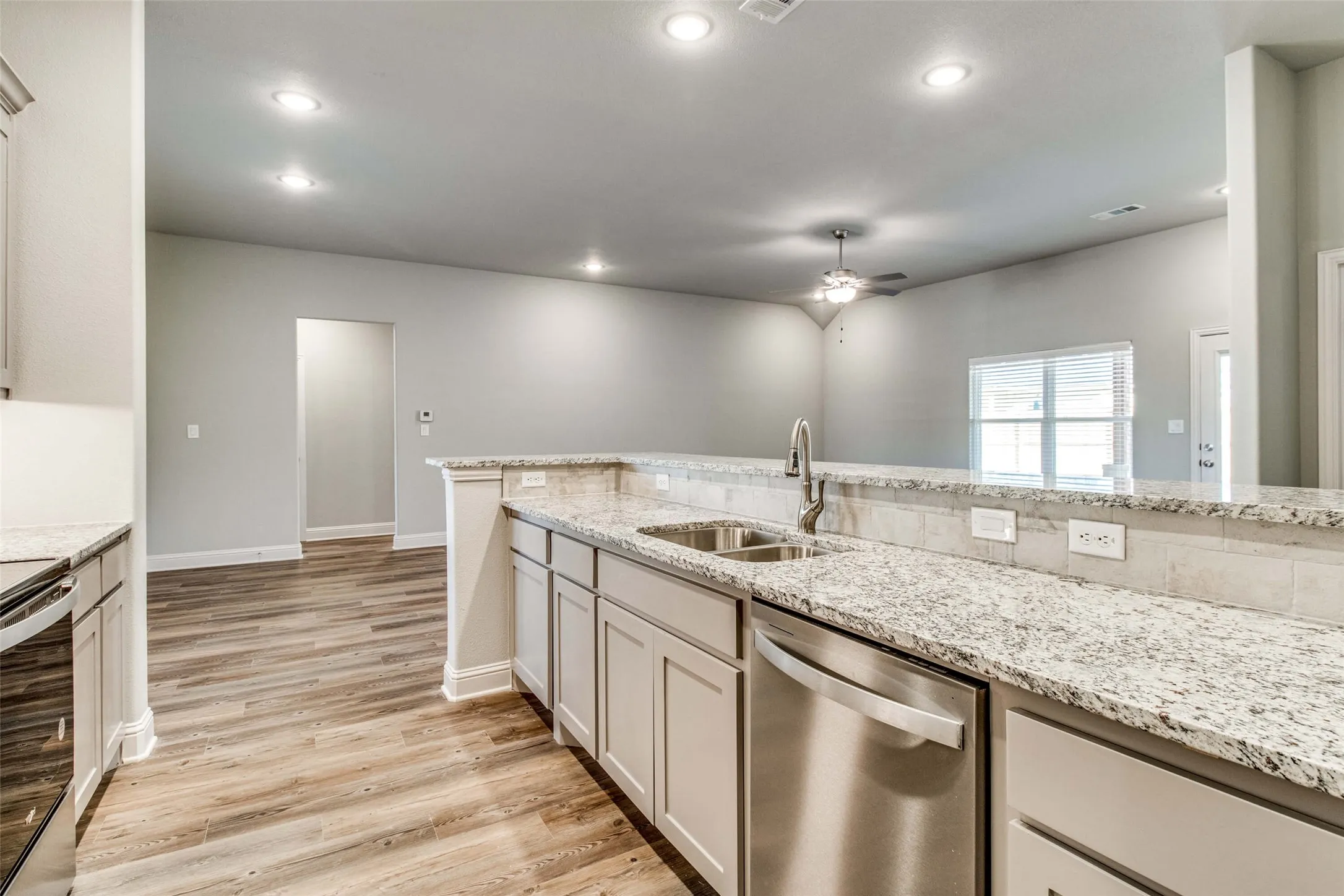 Kitchen featuring light-toned cabinetry, stainless steel appliances, a double basin sink with a high-arc faucet, and speckled countertops