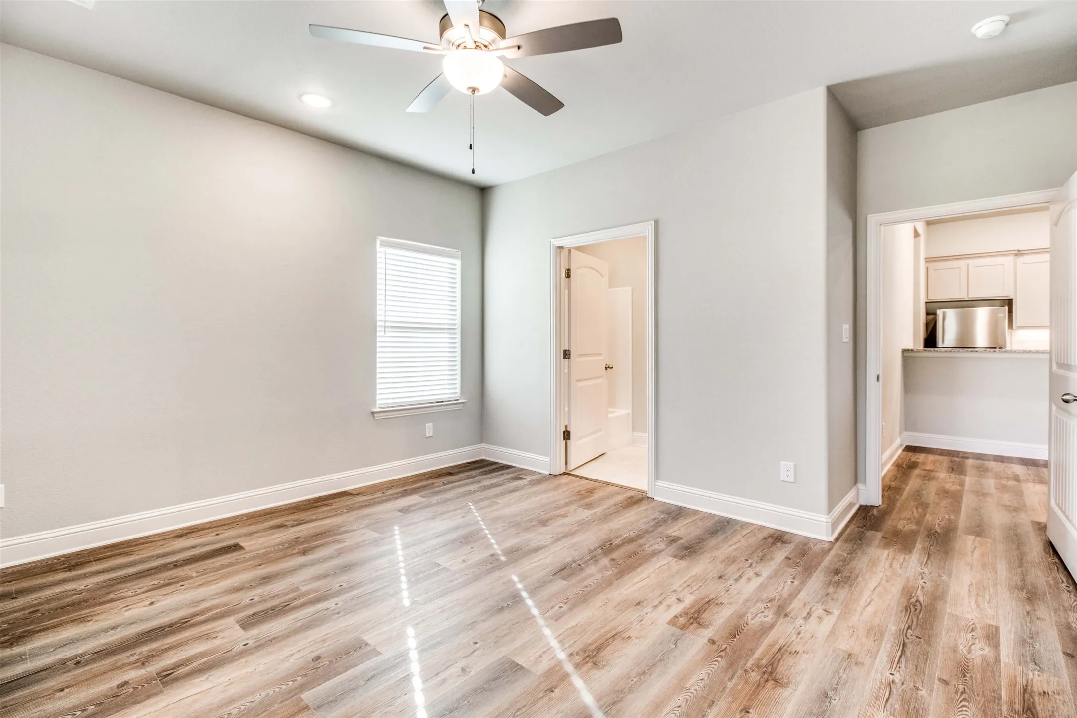 Spacious room featuring wood-finish flooring, a ceiling fan with integrated lighting, and recessed ceiling lights