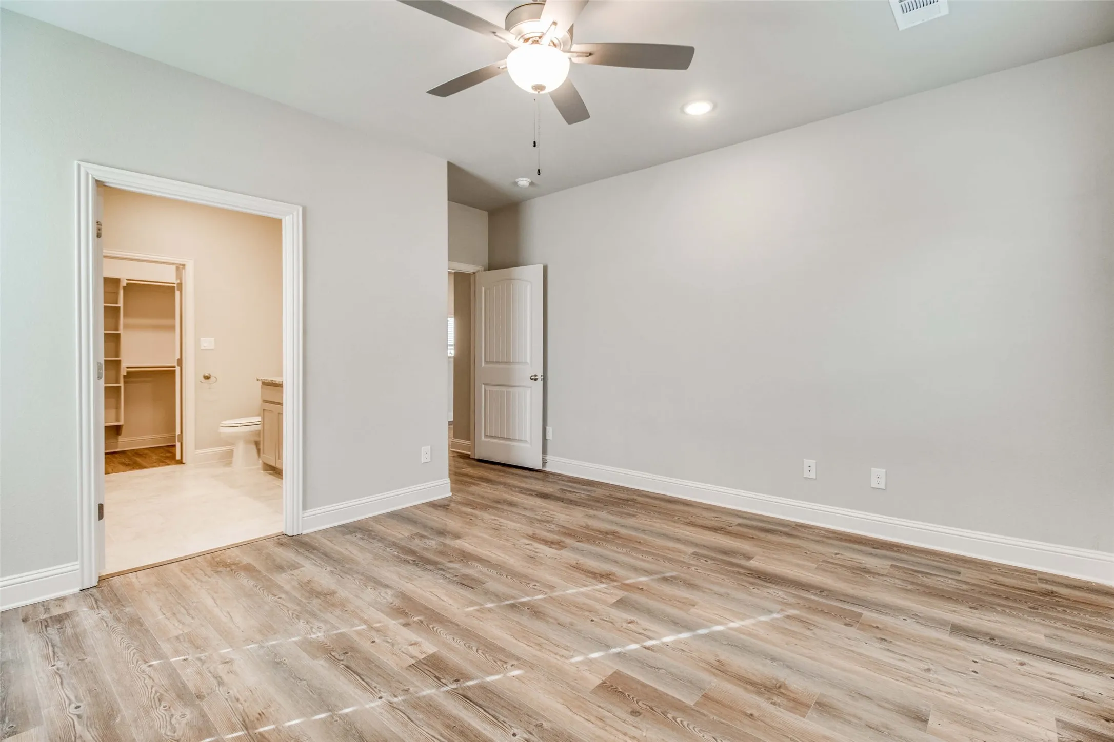 Spacious room featuring wood-finish flooring, a ceiling fan with integrated lighting, and recessed lighting