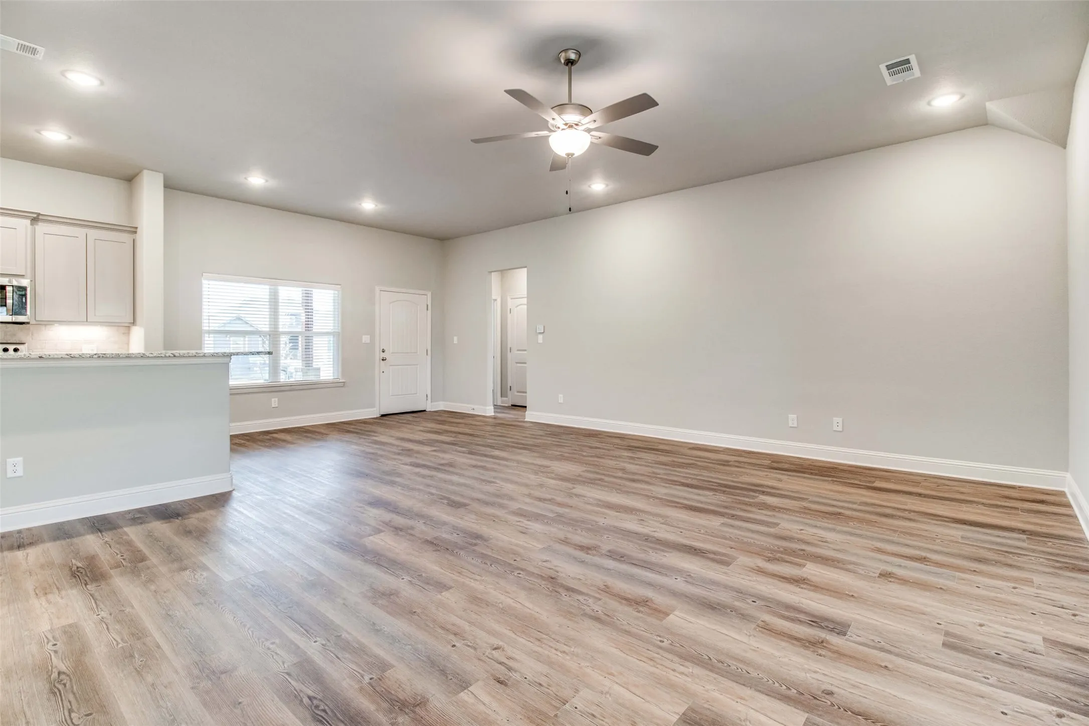 Open-concept living area featuring wood-finish flooring, recessed lighting, and a ceiling fan