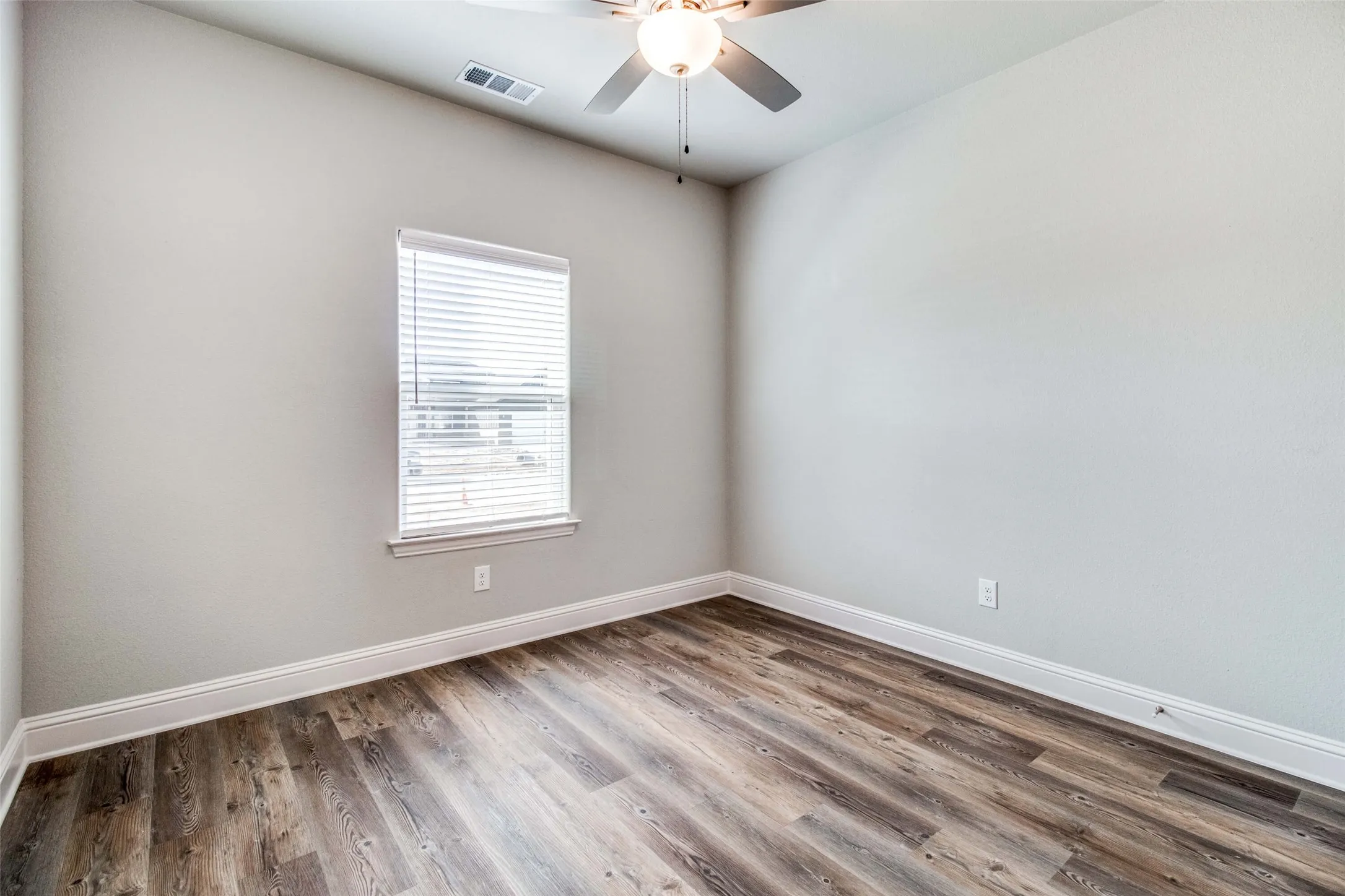 Wood-finish flooring, single window with blinds, ceiling fan with integrated lighting, light neutral wall color, and white trim