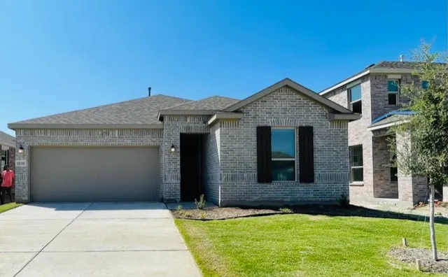 Brick exterior with a gabled roofline, attached garage, and a concrete driveway