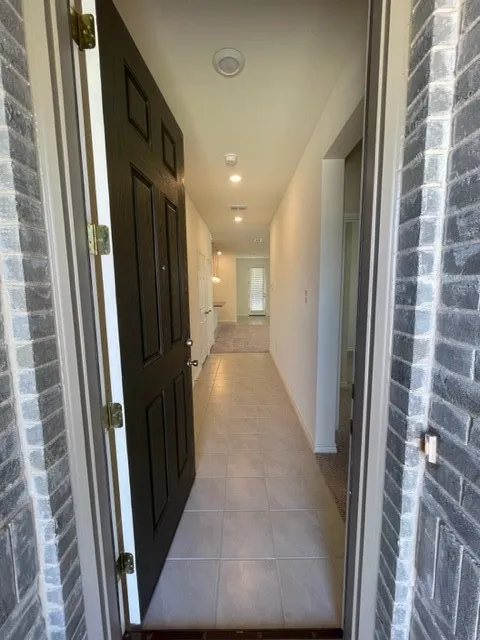 Entryway featuring a dark paneled door, gray brick exterior, light-toned tile flooring, and recessed ceiling lighting