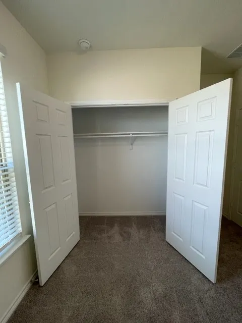 Carpeted flooring, paneled closet doors, and interior shelving