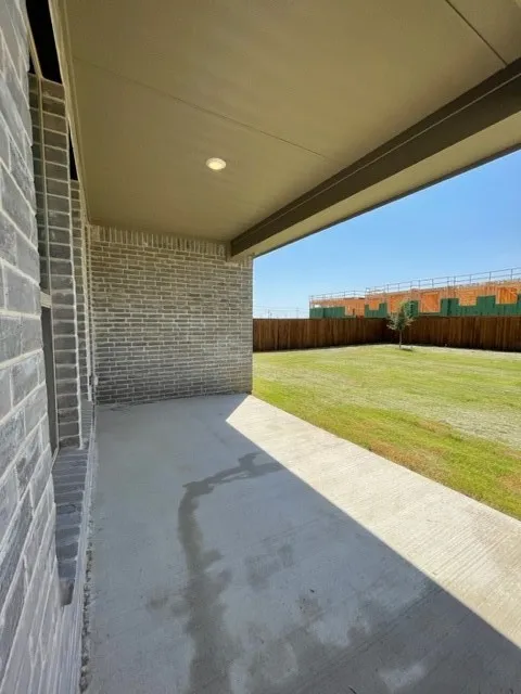Covered patio featuring a recessed light fixture, a concrete surface, and a brick exterior