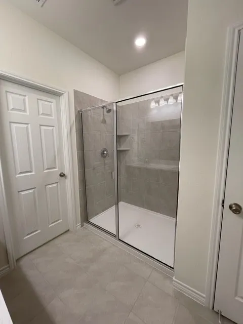 Glass-enclosed shower with tile surround, built-in shelving, and a polished chrome shower system