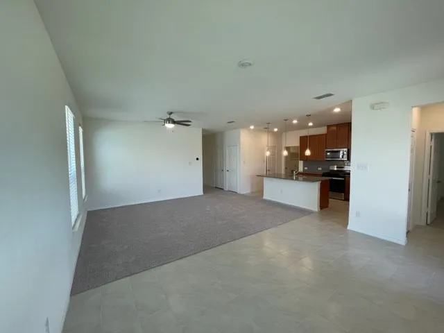 Open-concept living space featuring a ceiling fan, recessed lighting, and a kitchen island with pendant lighting