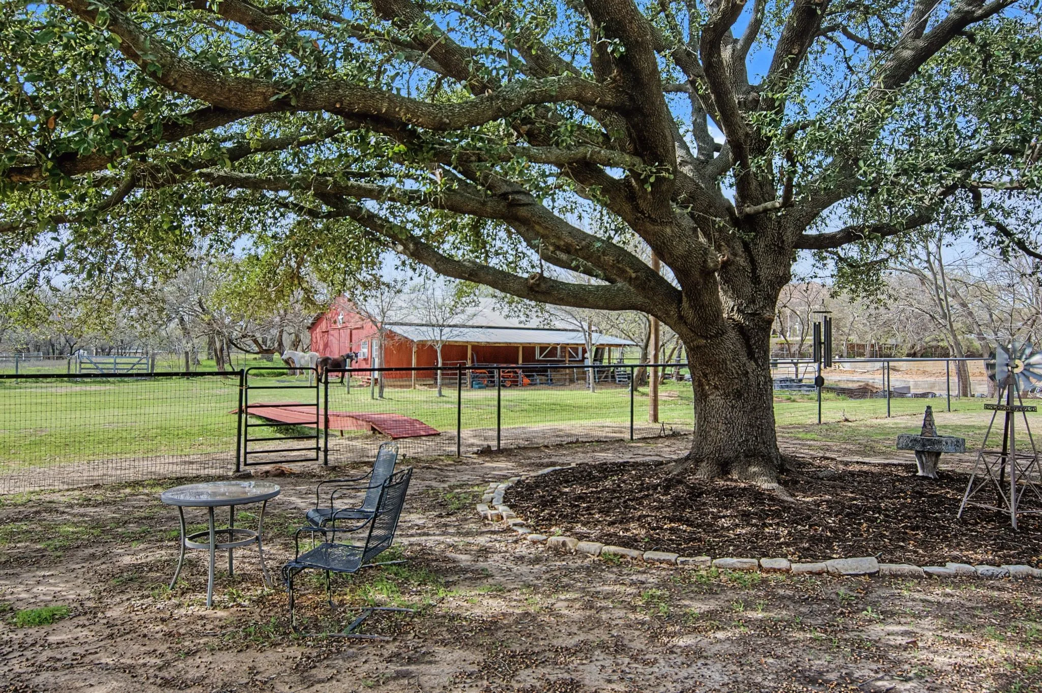 Expansive yard featuring a mature tree, red barn structure, and perimeter fencing