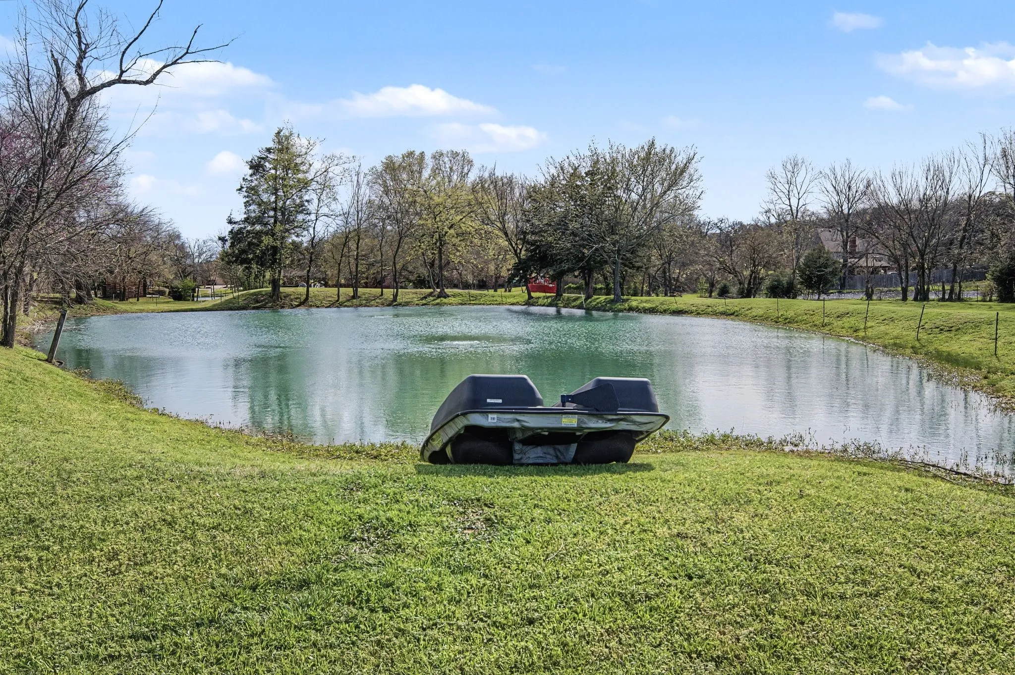 Expansive green lawn with a large pond