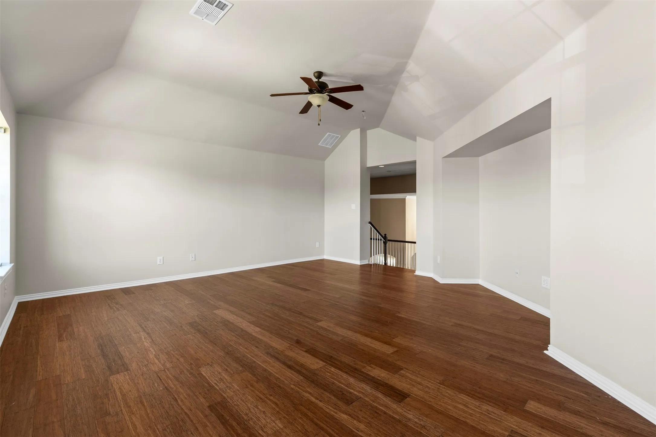 Vaulted ceiling with a ceiling fan, wood-finish flooring, and white trim