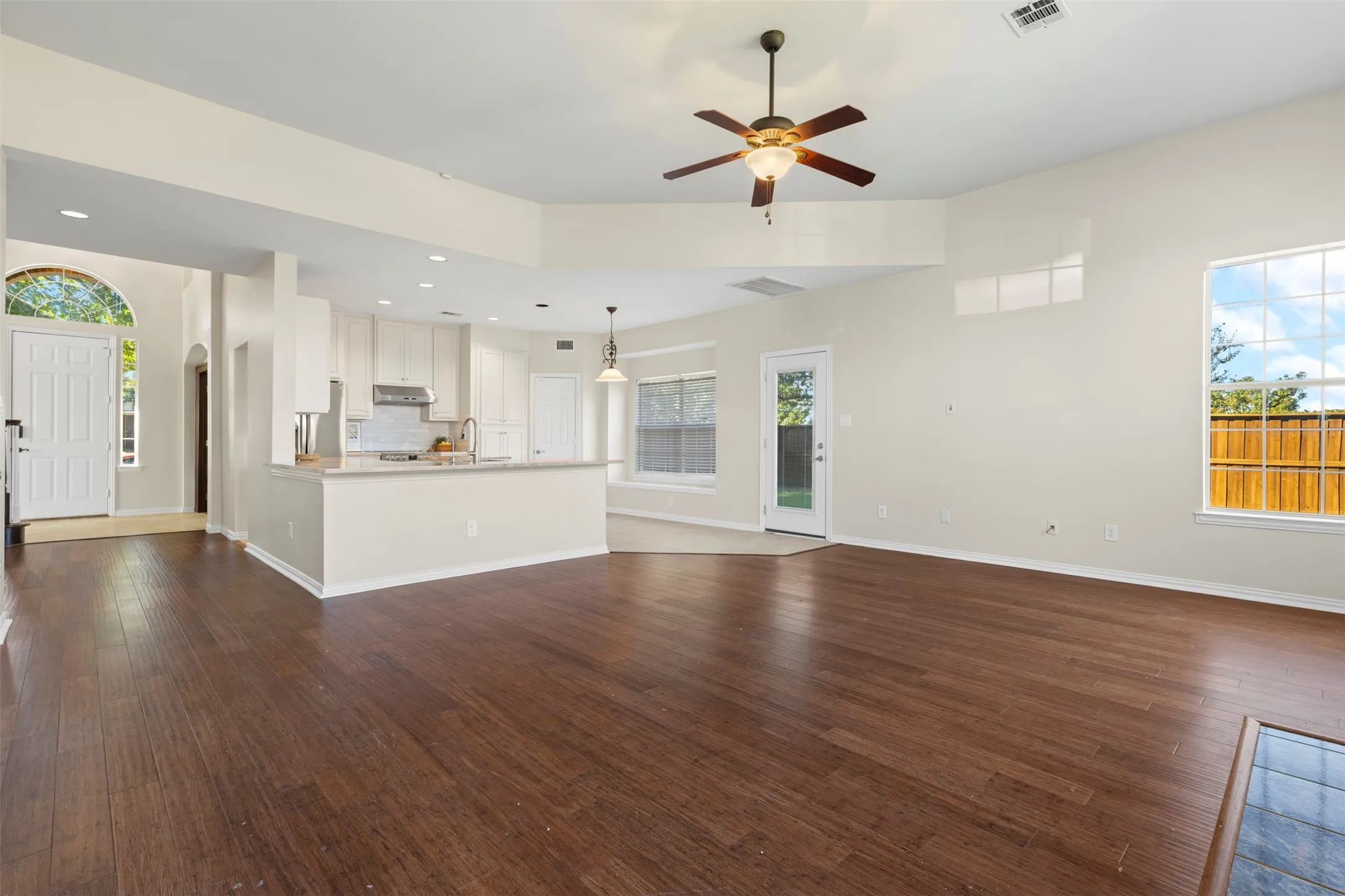 Expansive living area with wood-finish flooring, vaulted ceilings, and a ceiling fan