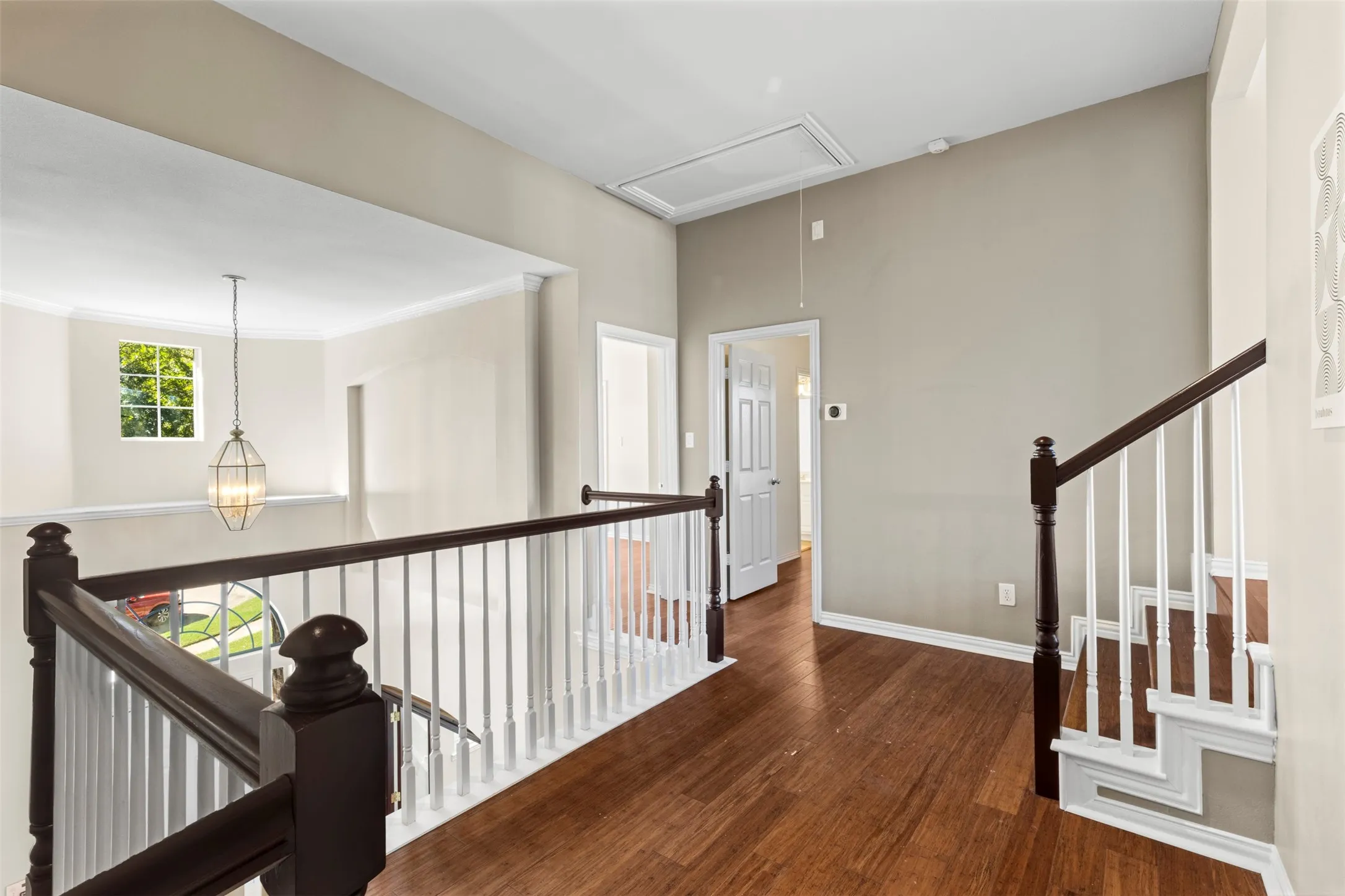 Hardwood flooring, painted walls, white trim, open railing, and a decorative pendant light fixture
