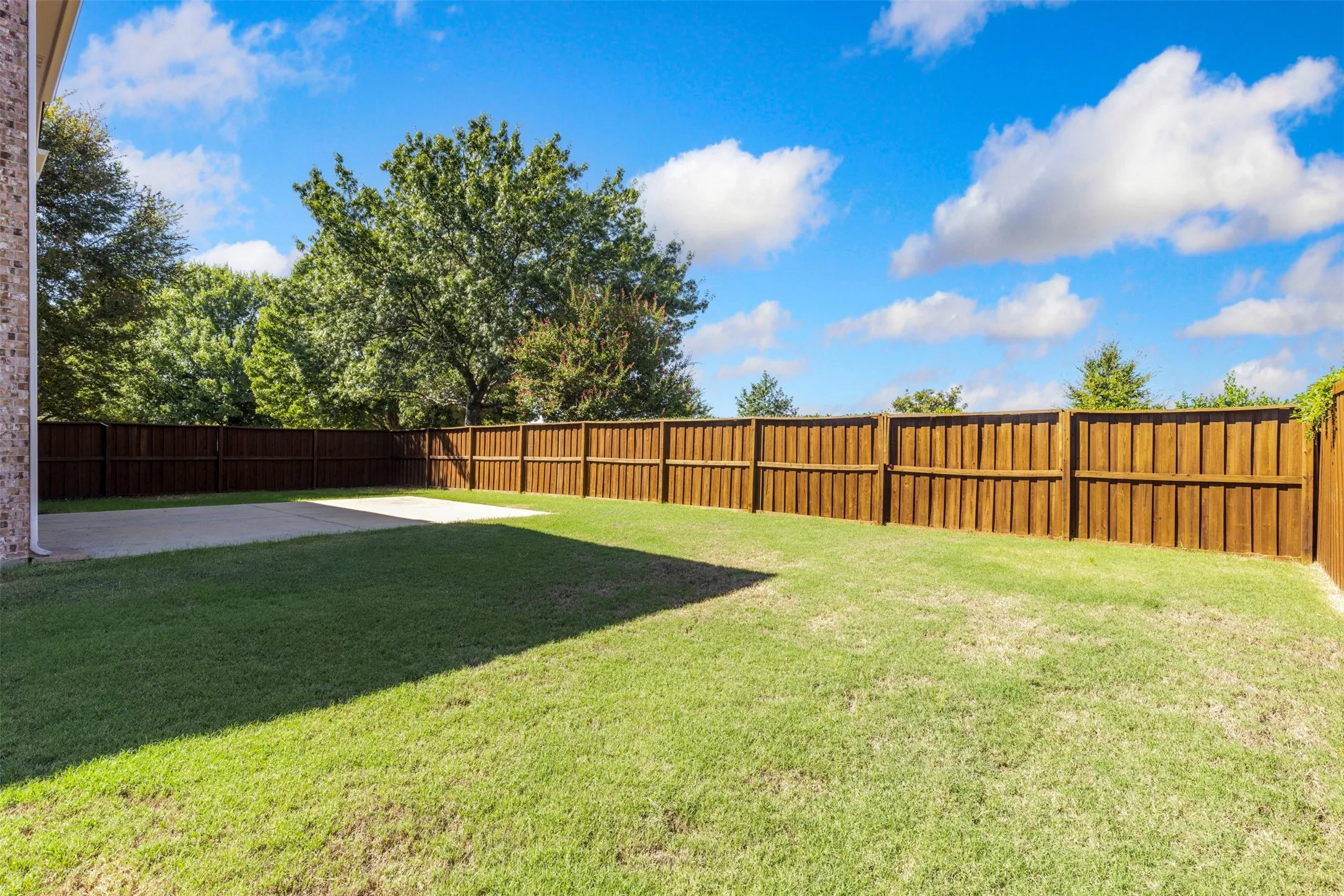 Expansive backyard featuring a lush lawn, a sizable concrete patio, and a full privacy fence