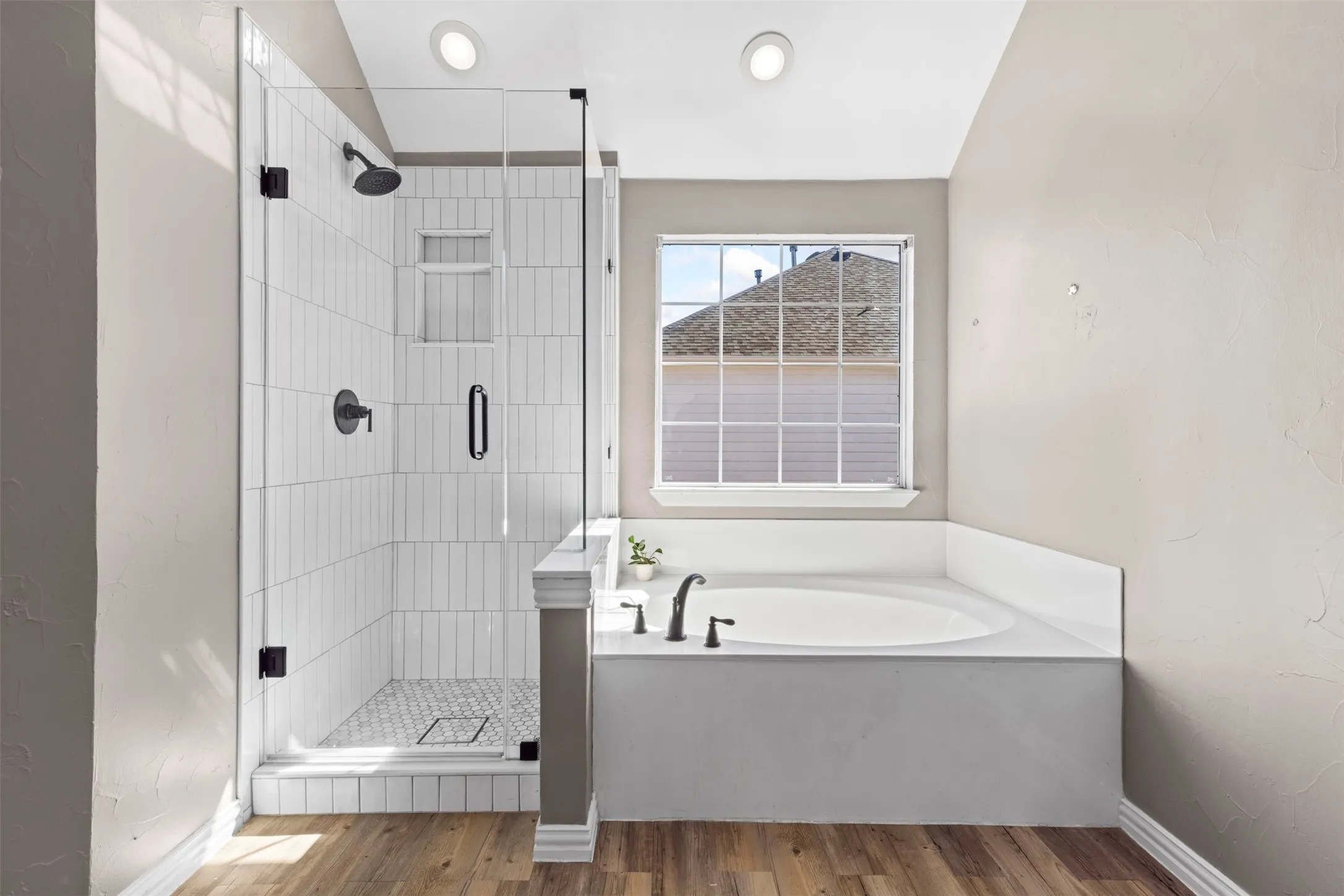 Glass-enclosed shower with vertical tile surround and black fixtures
