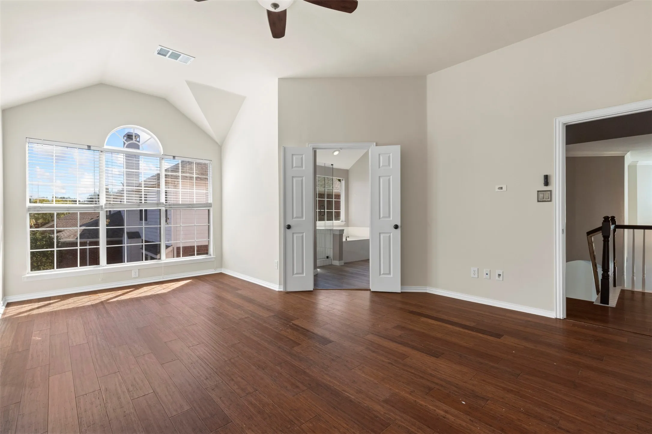 Vaulted ceiling, wood-finish flooring, architectural windows, ceiling fan, and double doors