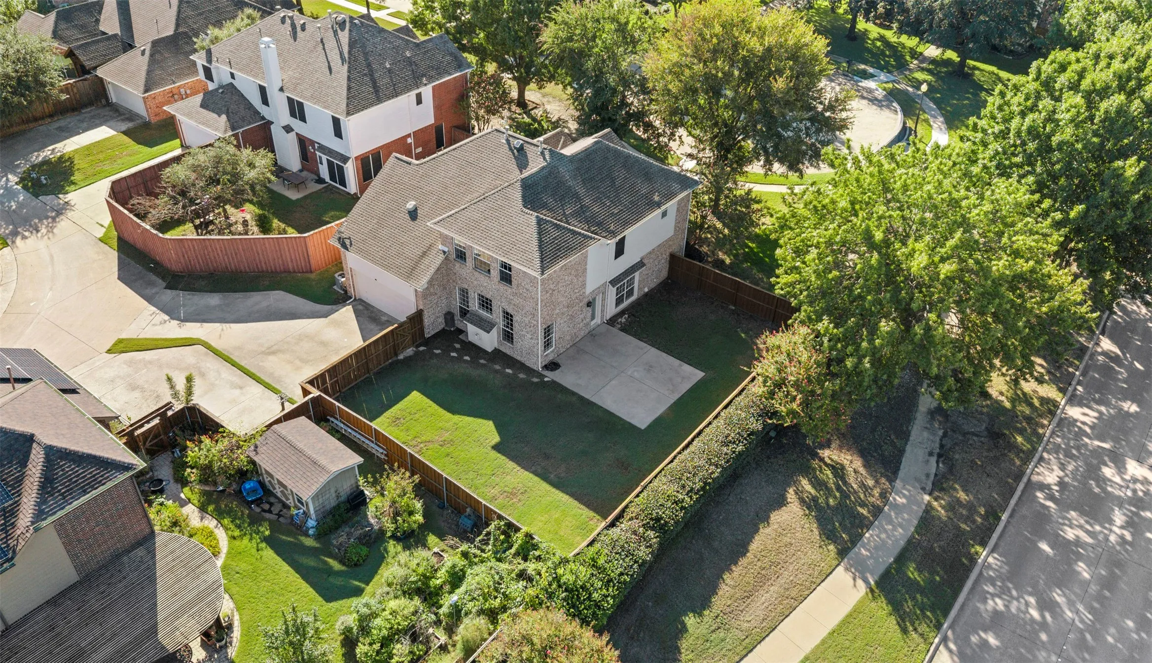Two-story residence with a brick and siding exterior, an attached two-car garage, a fenced backyard with a patio, and a separate storage shed