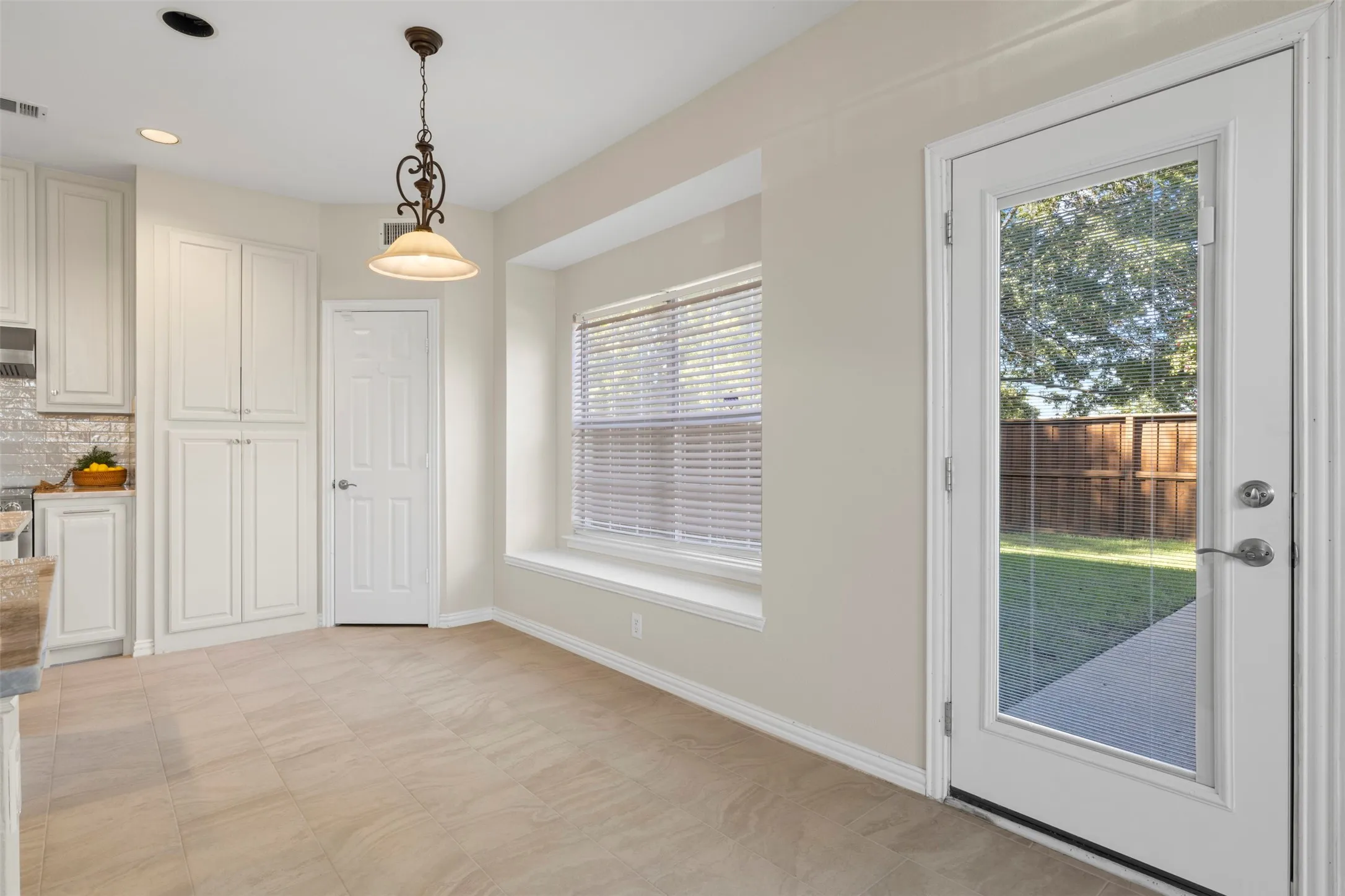 Light-toned tile flooring, recessed lighting, and a decorative pendant light fixture