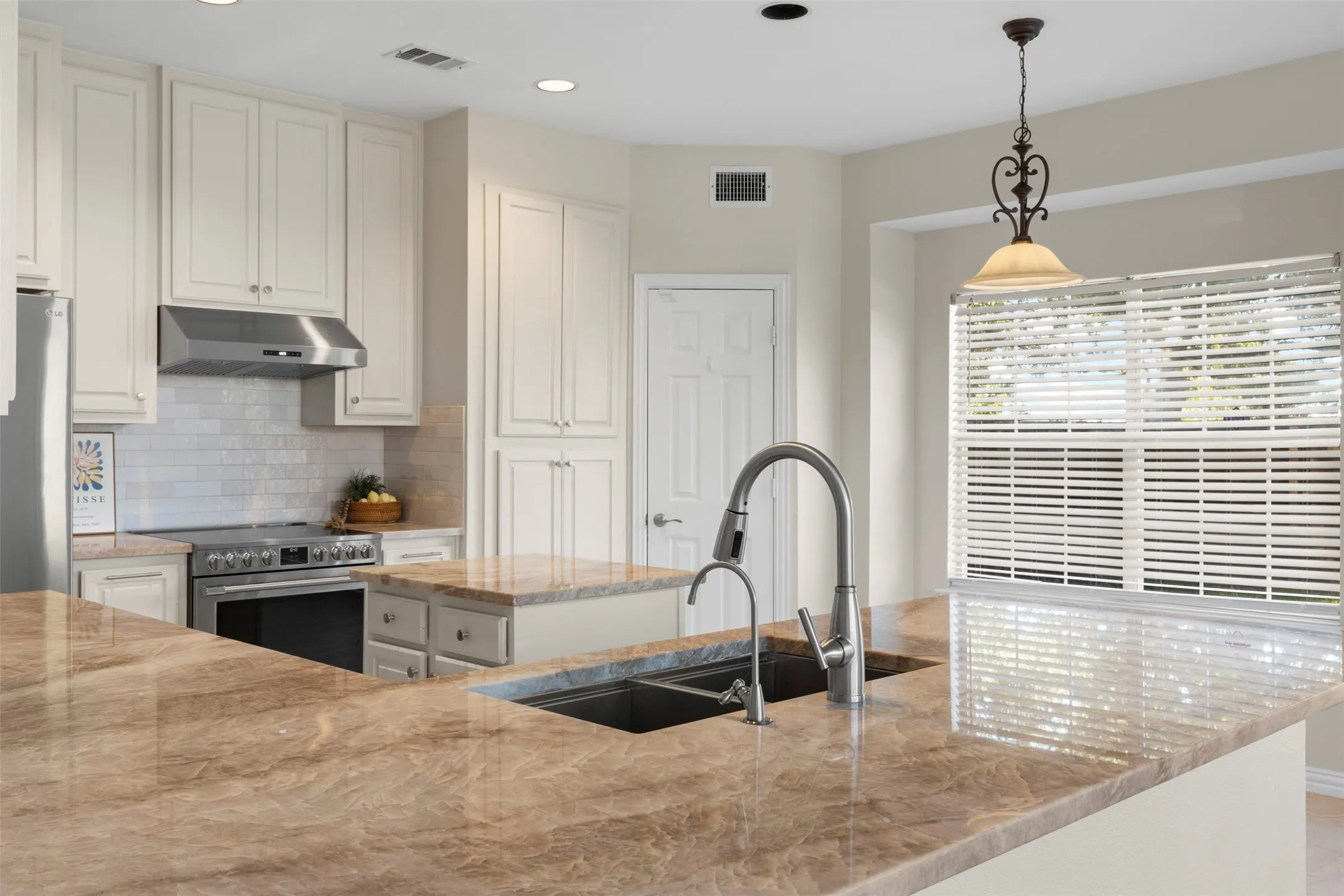 Expansive countertops, stainless steel appliances, integrated sink, pendant lighting, and recessed lighting