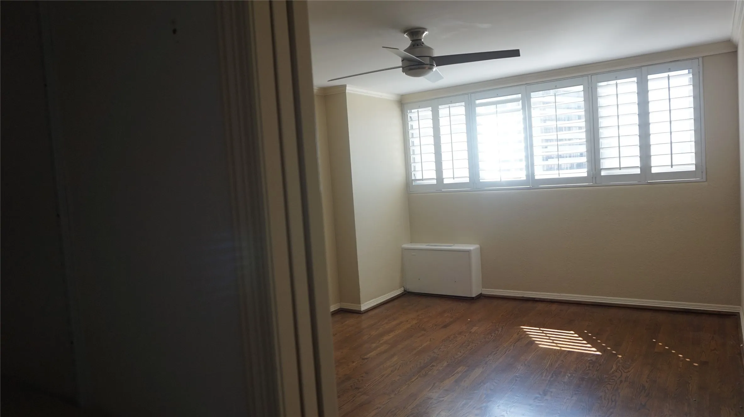 Hardwood-style flooring, a ceiling fan, and window shutters