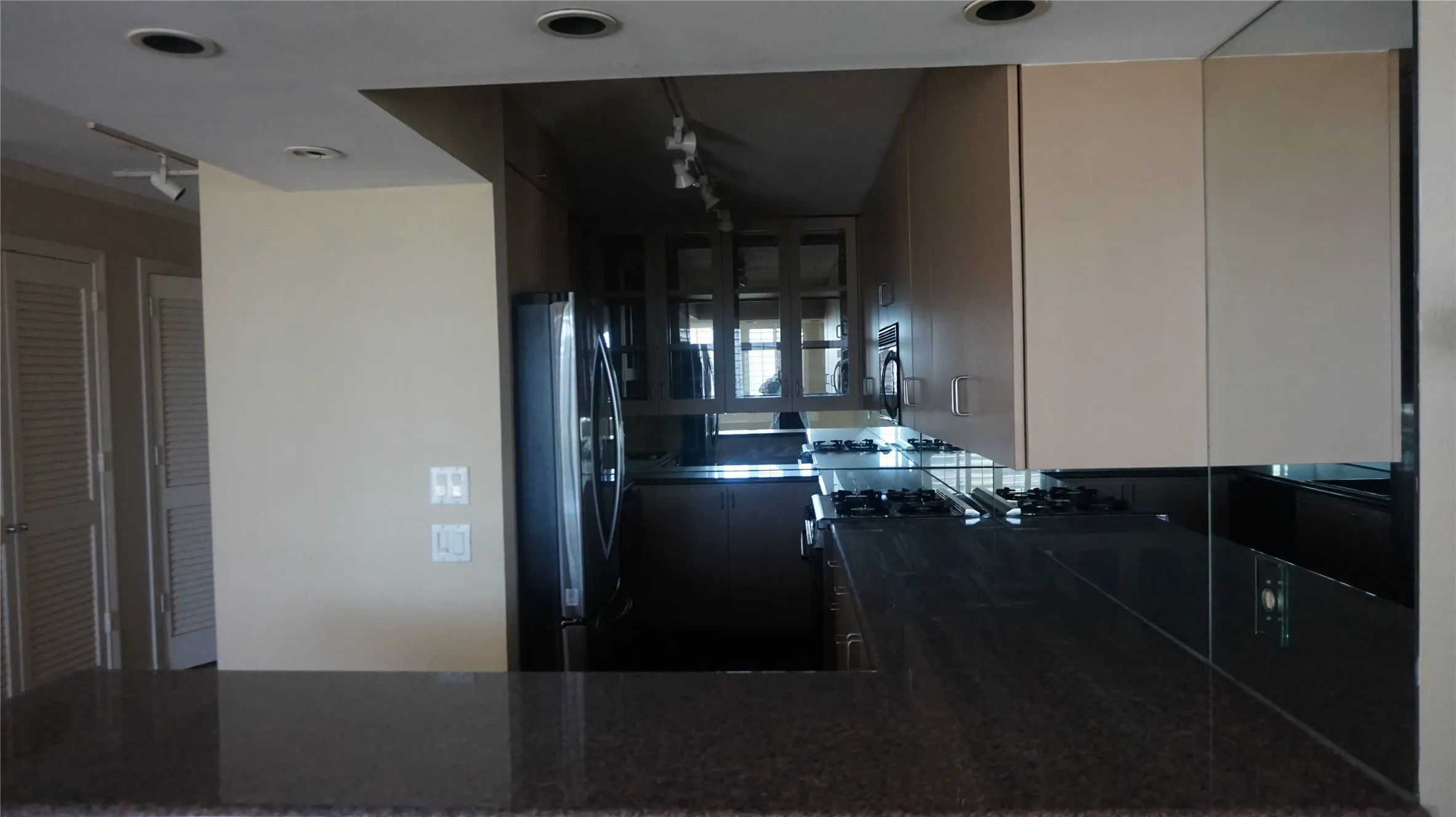 Kitchen featuring light-toned cabinetry, a built-in oven, gas cooktop, and dark stone-finish countertops
