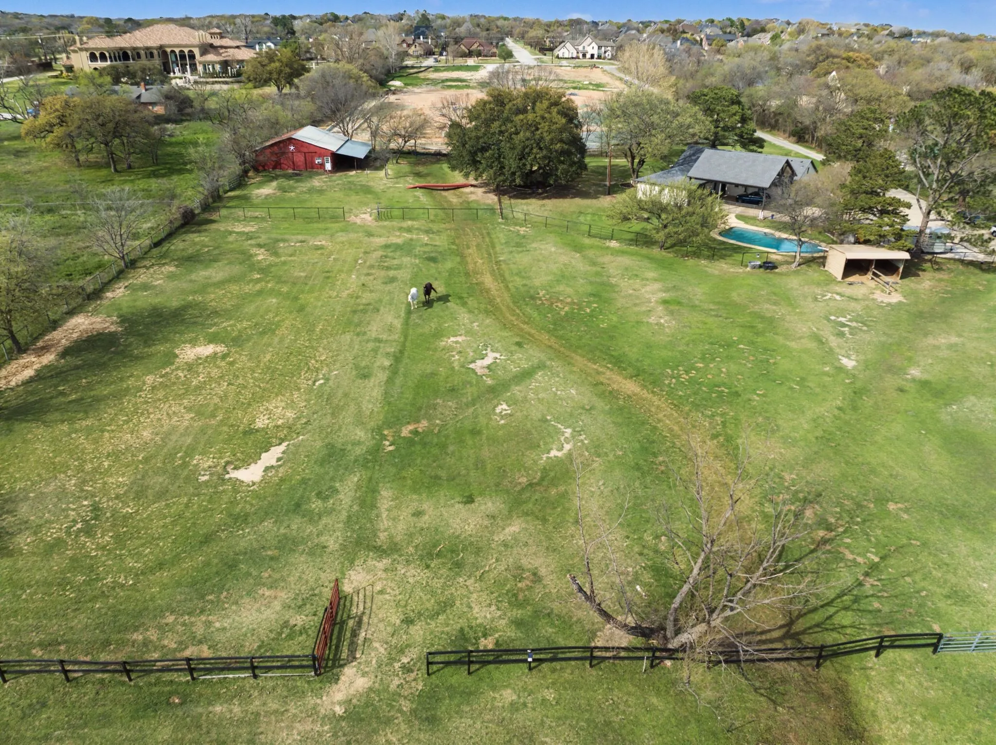 Expansive acreage featuring a private swimming pool, a red barn structure, and a fenced perimeter