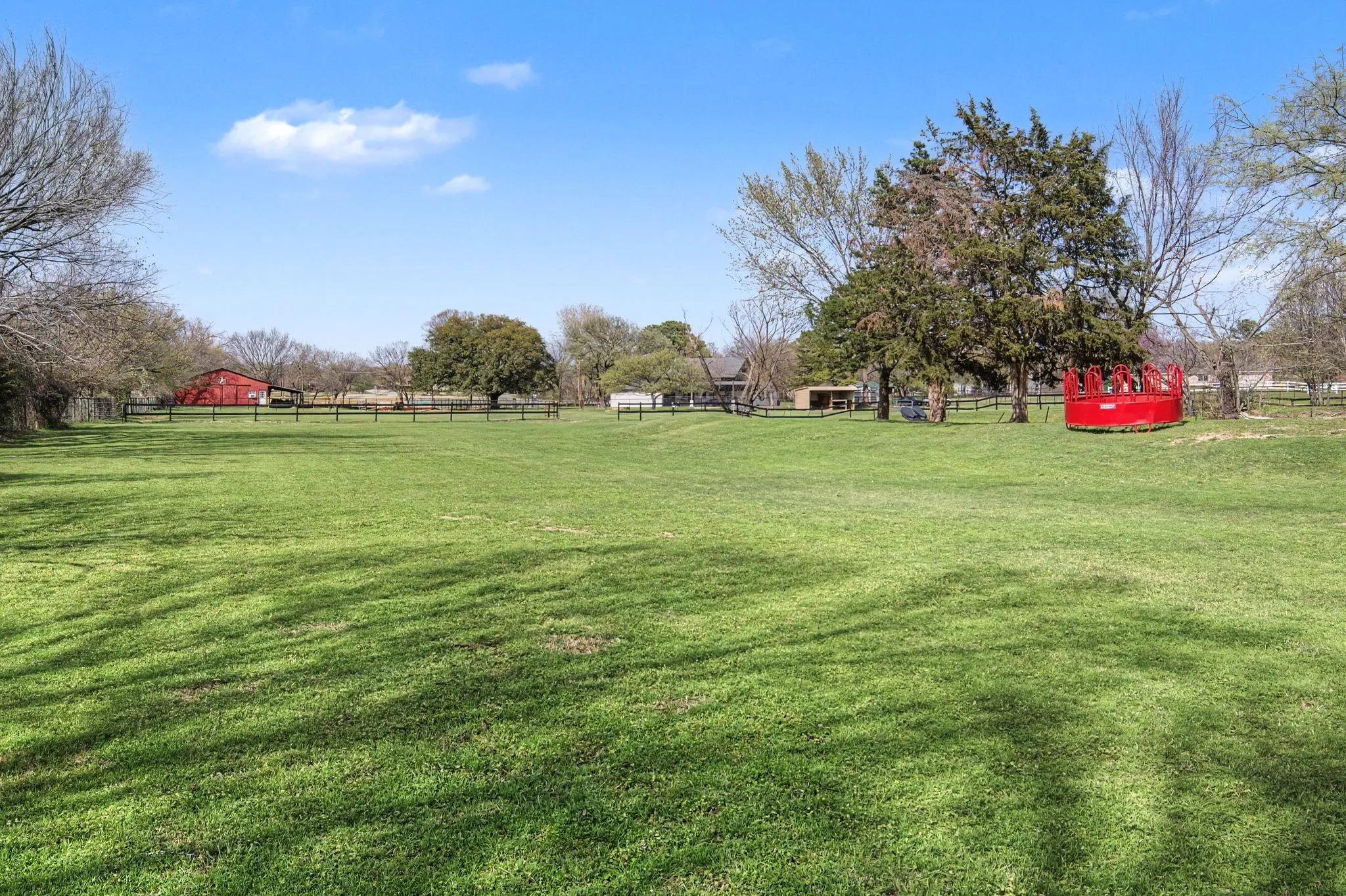 Expansive grassy yard with mature trees and a fenced perimeter