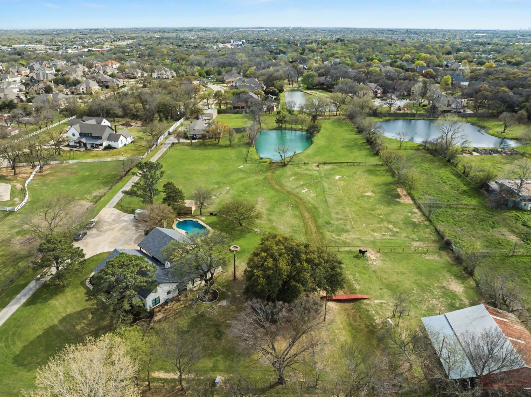 Expansive property featuring a private swimming pool, multiple ponds, vast green spaces, and mature trees