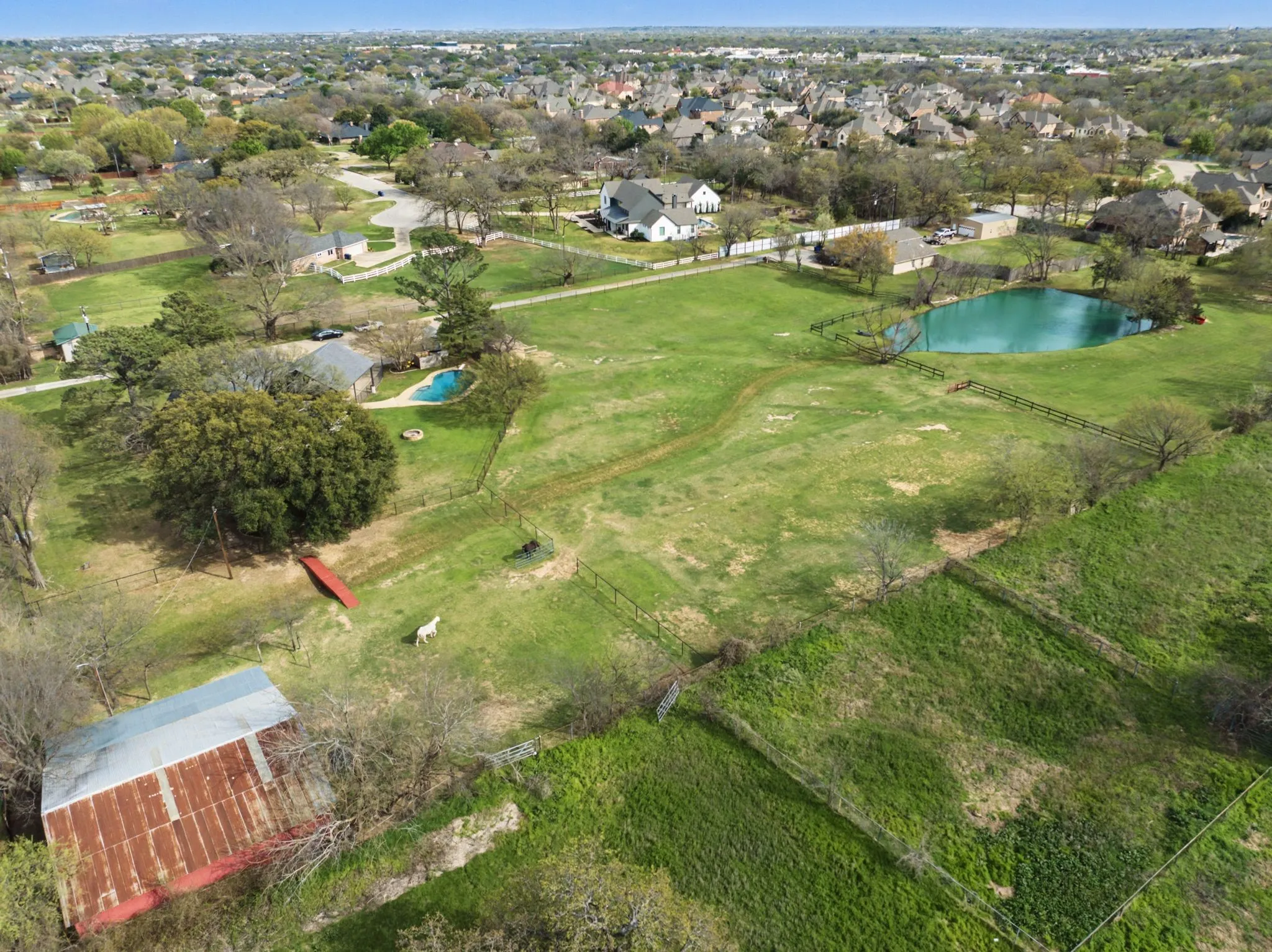 Expansive green spaces with a private pond, a residential structure, a swimming pool, and a barn