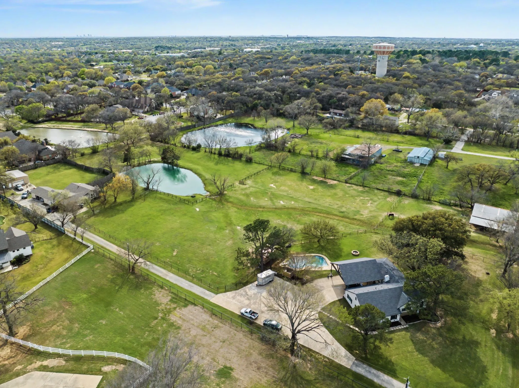 Expansive green acreage featuring multiple ponds, perimeter fencing, and mature trees