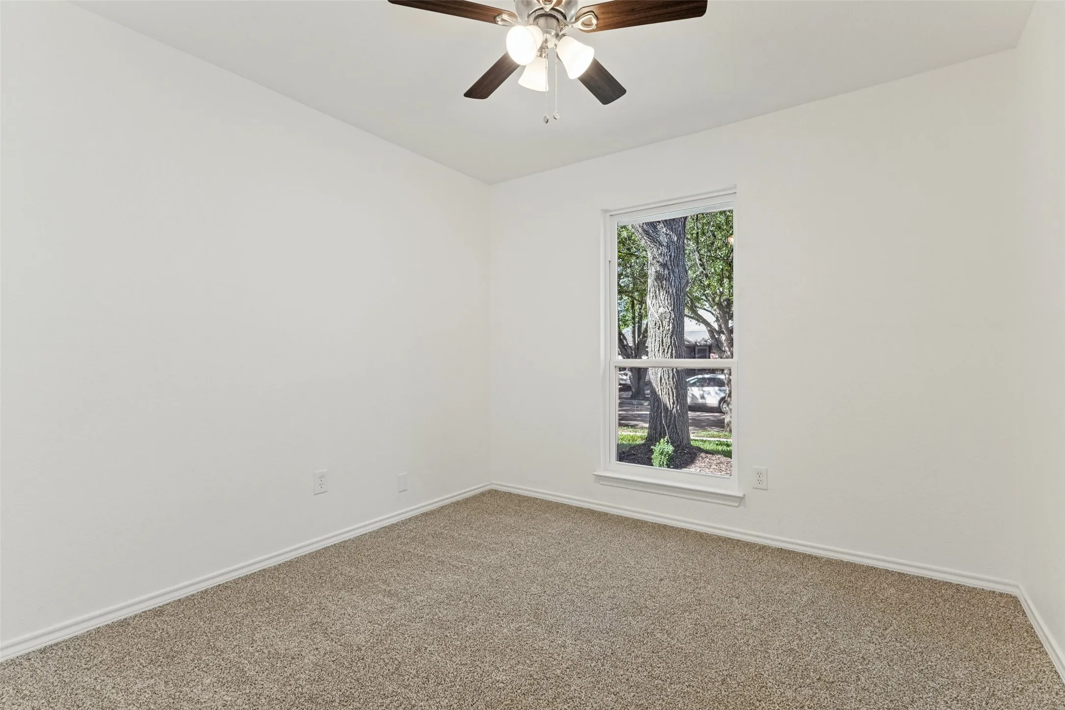 Neutral carpeted flooring with white wall finishes, a single-pane window, and an installed ceiling fan