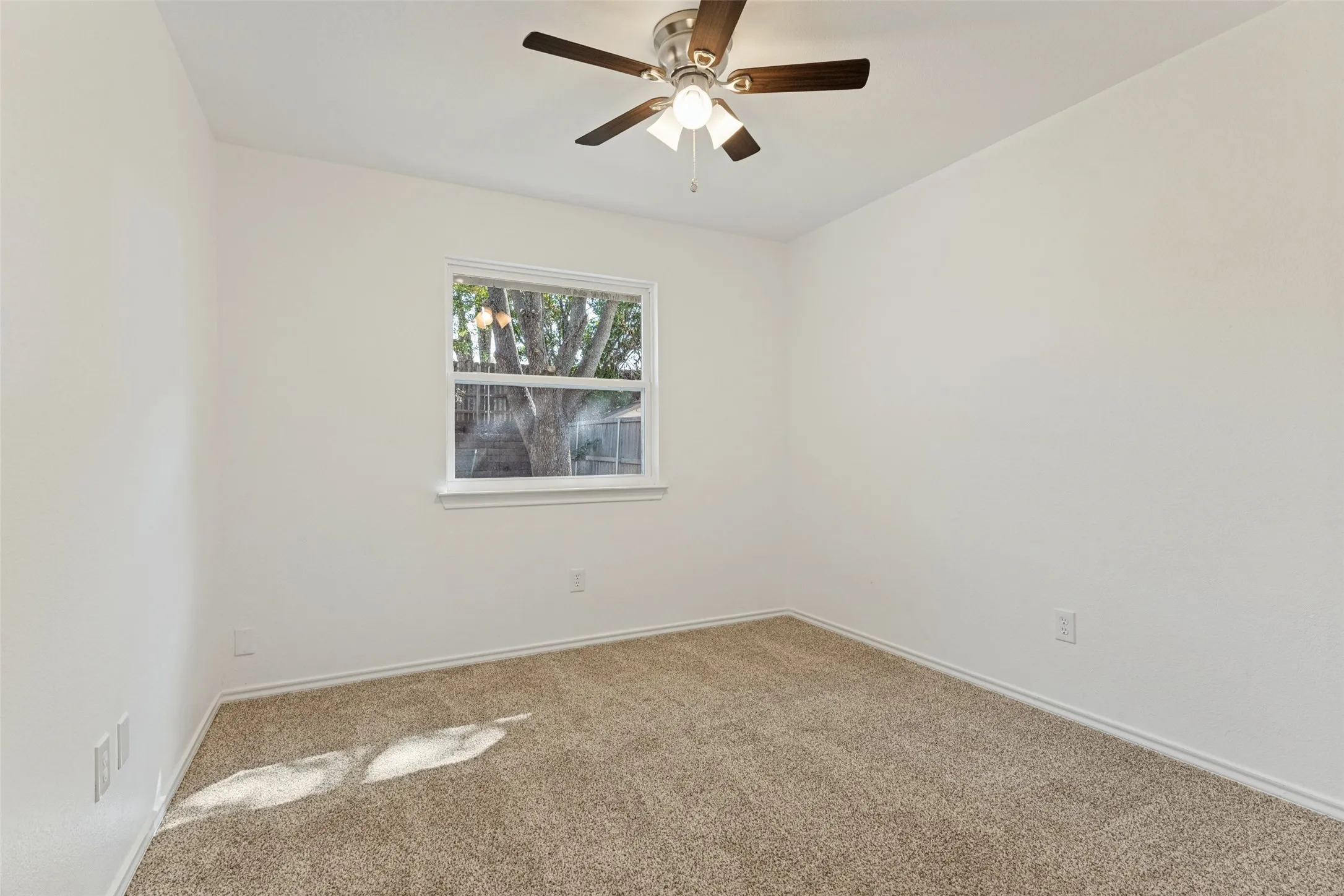 Neutral wall palette with a ceiling fan light fixture, window, and carpeted flooring