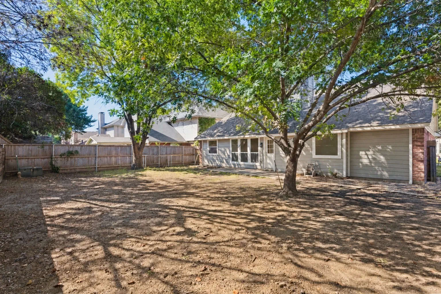 Spacious backyard with mature trees, wood fence, and a screened-in porch