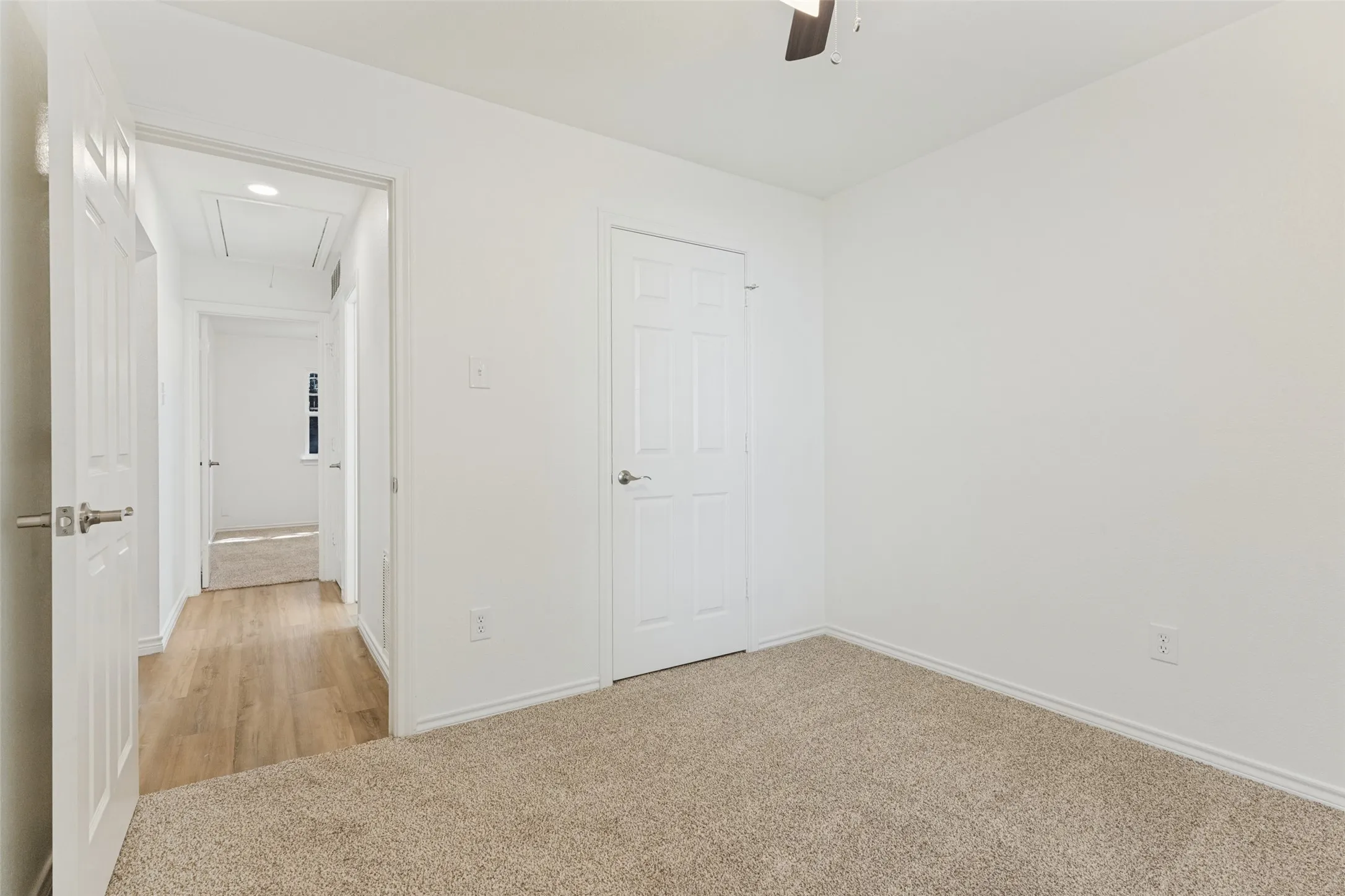 Carpeted flooring, white interior doors, and a ceiling fan
