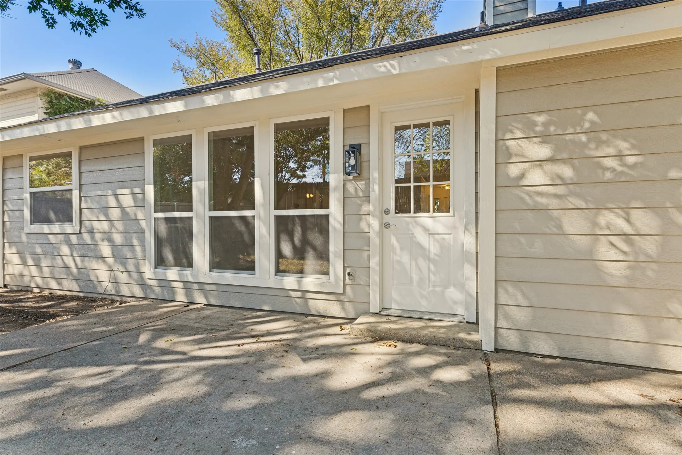 Exterior siding in a neutral tone, multiple windows, and a glass-paneled door