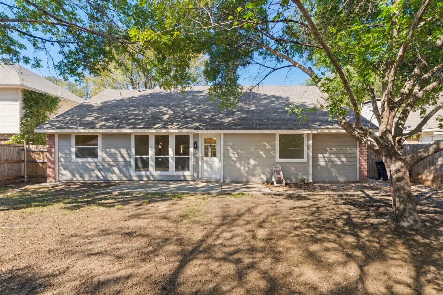 Rear exterior with wood fencing, a patio, and a shingled roof