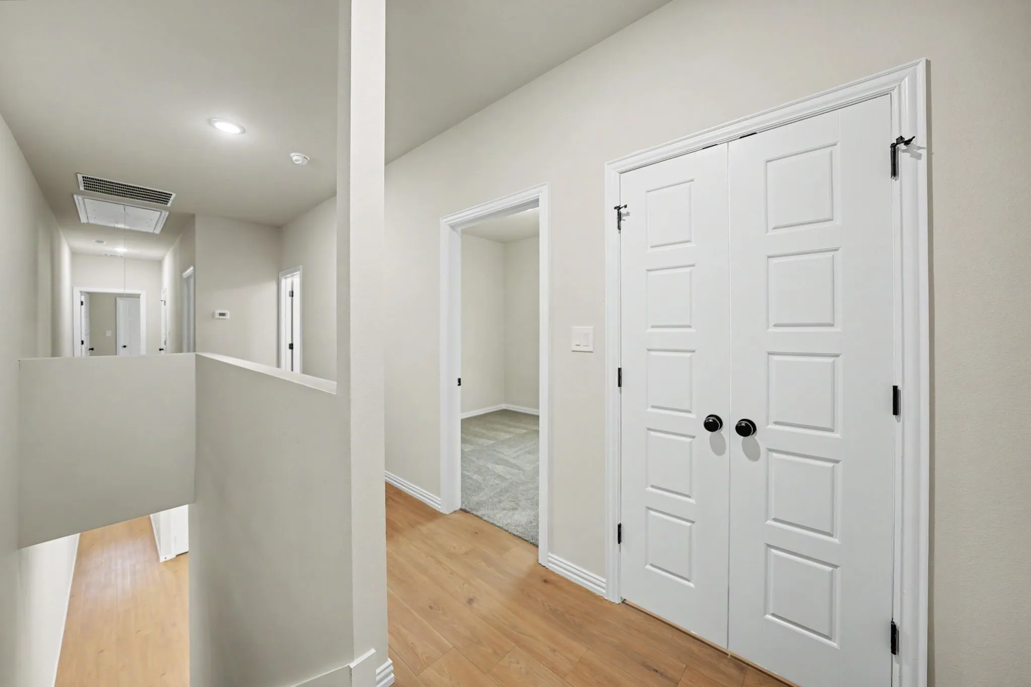Hallway with wood-finish flooring, recessed lighting, and white walls