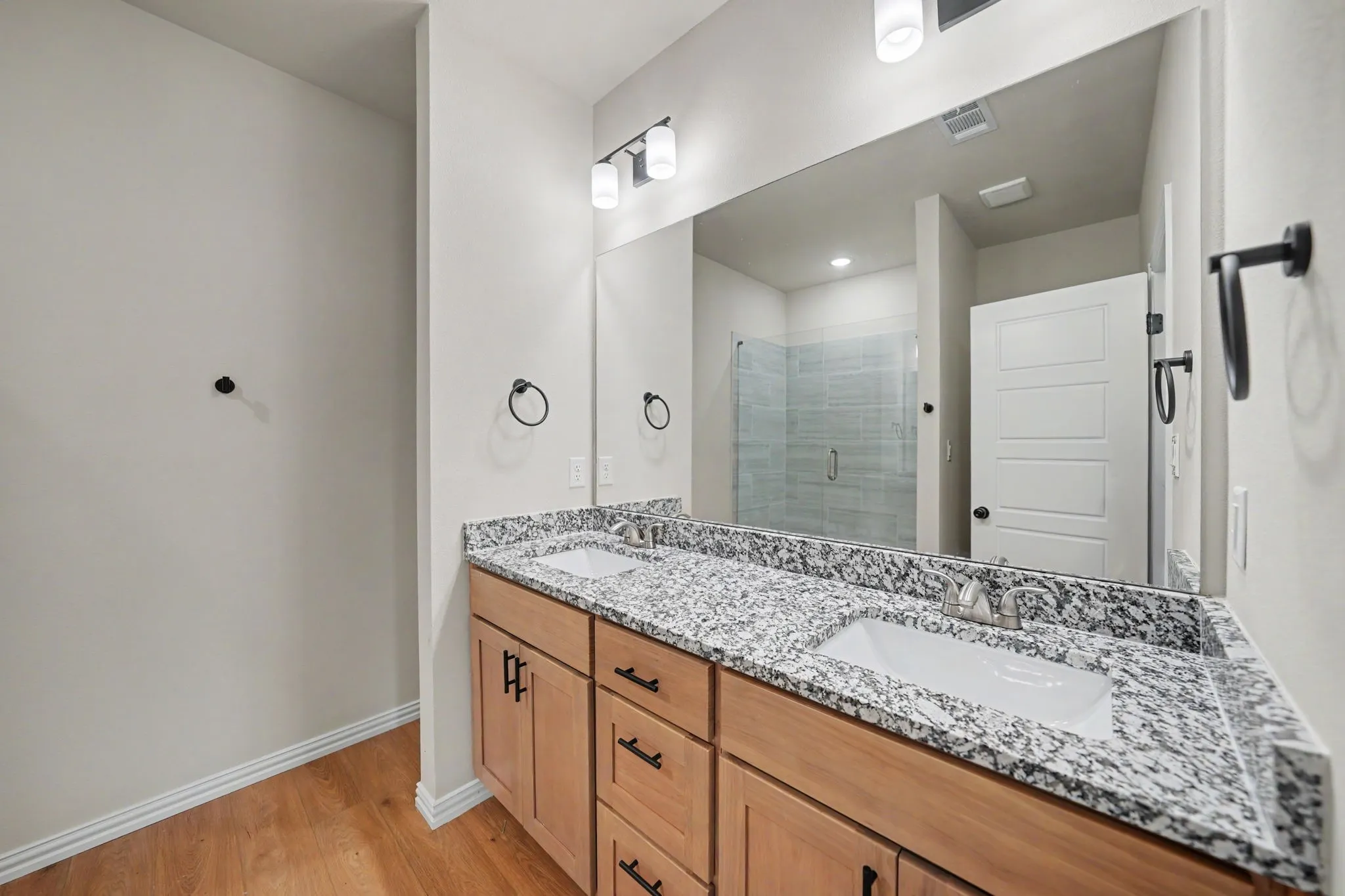 Double vanity with wood-finish cabinetry, speckled countertops, and undermount sinks